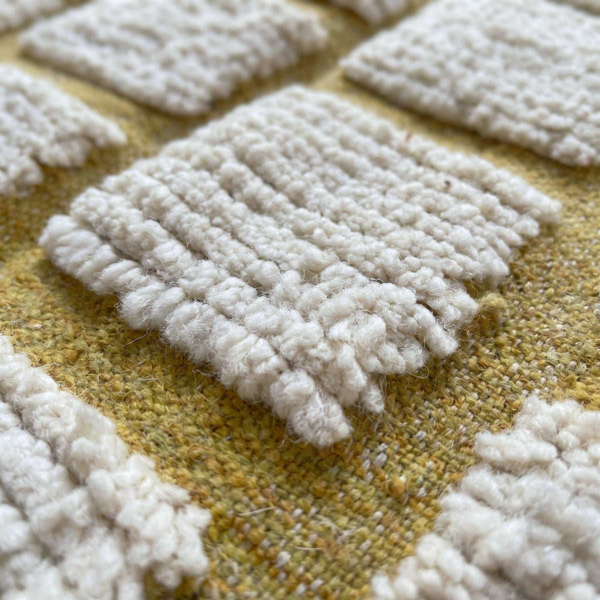 Gros plan sur un motif du tapis berbère Igoudar, grille moutarde régulière sur tout le champ