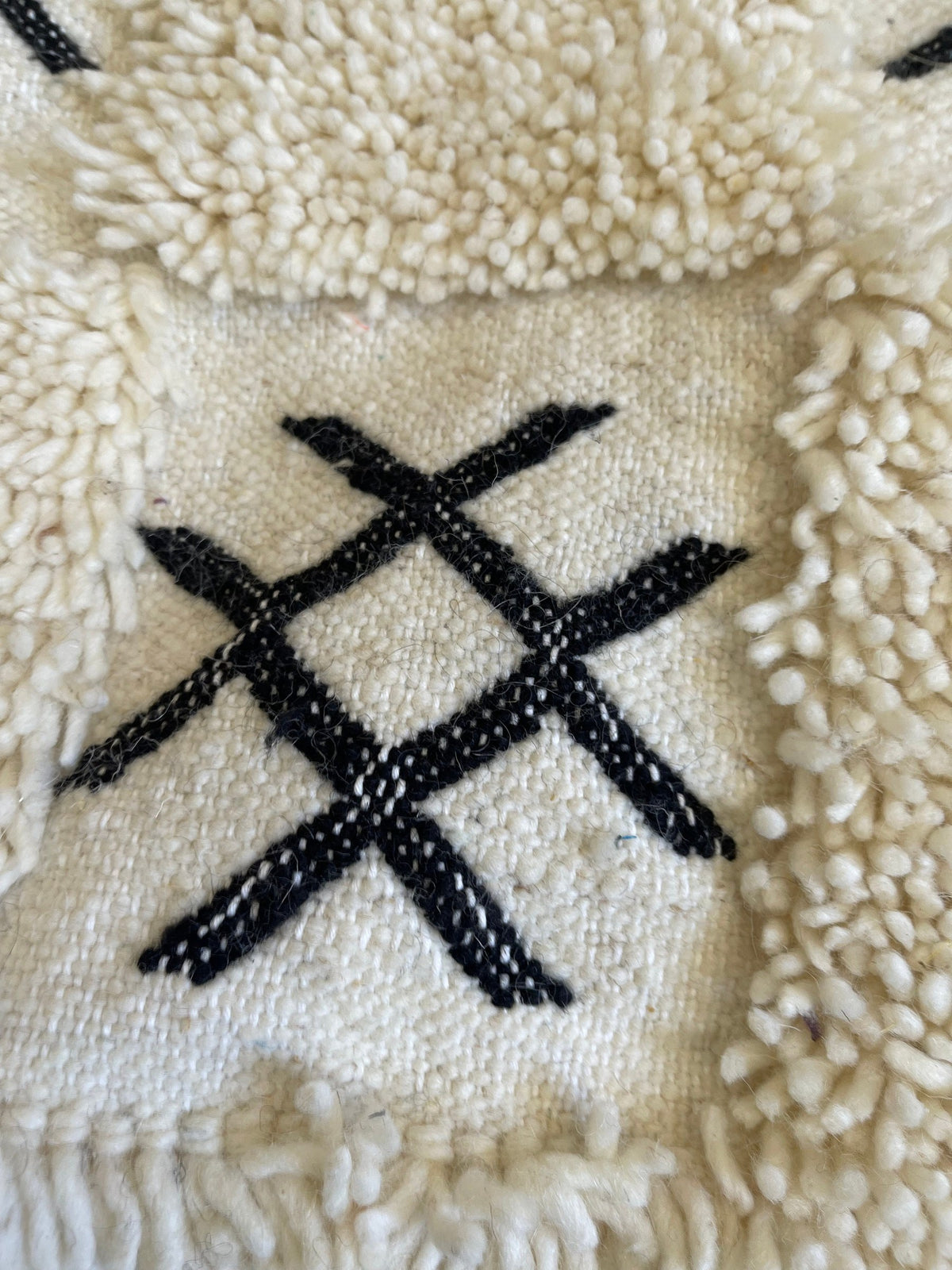 Gros plan sur la laine du tapis berbère Ouaneskra, nœuds serrés et tracé du motif de près