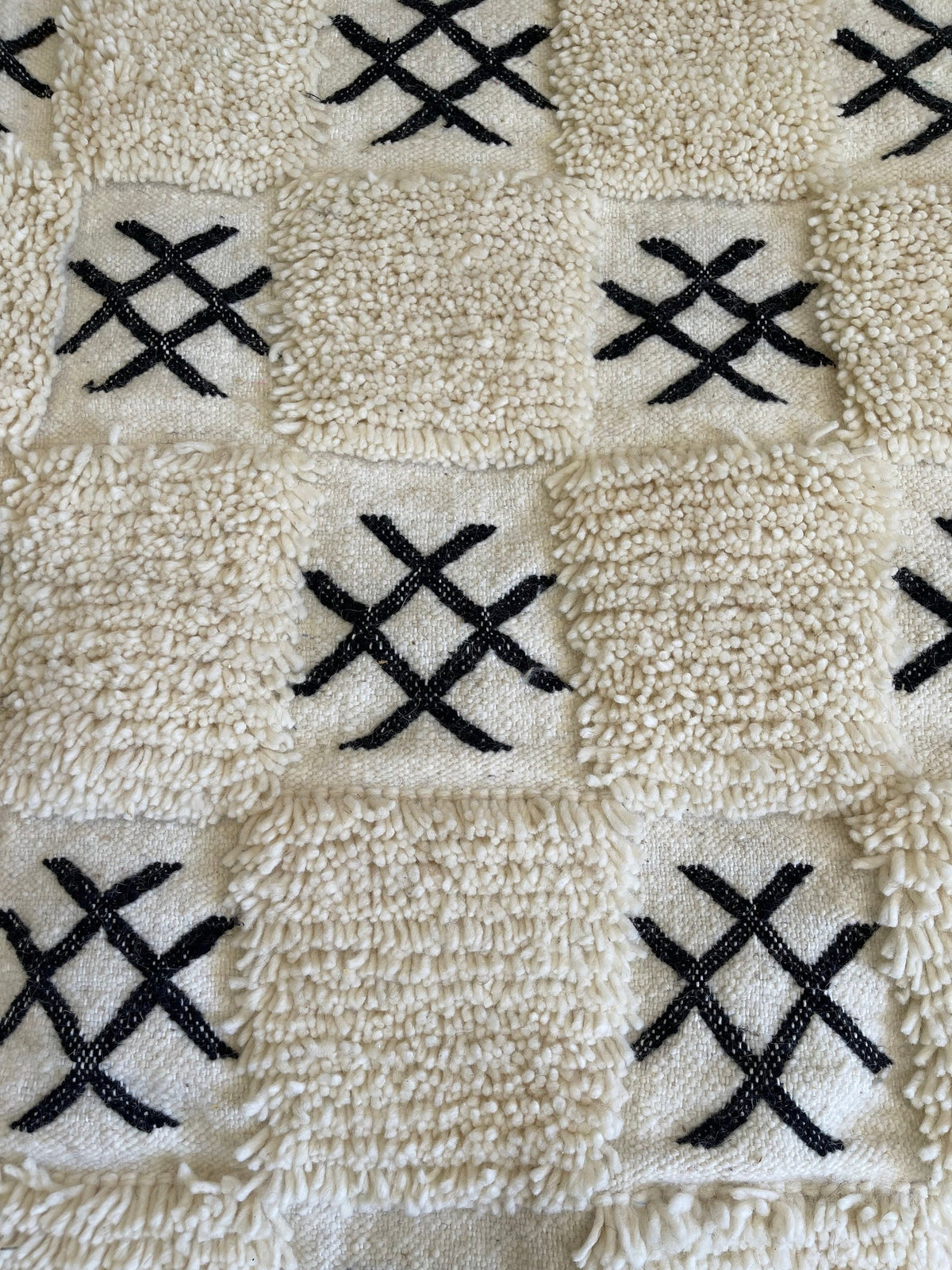 Gros plan sur un détail du tapis berbère Ouaneskra, poil moyen et motif blanc et noir vus de près