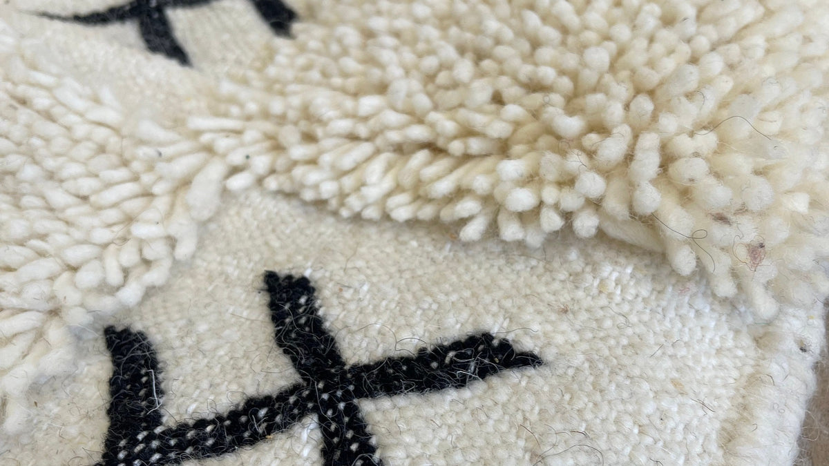 Gros plan sur la laine du tapis berbère Ouaneskra, poil blanc et noir noué à la main