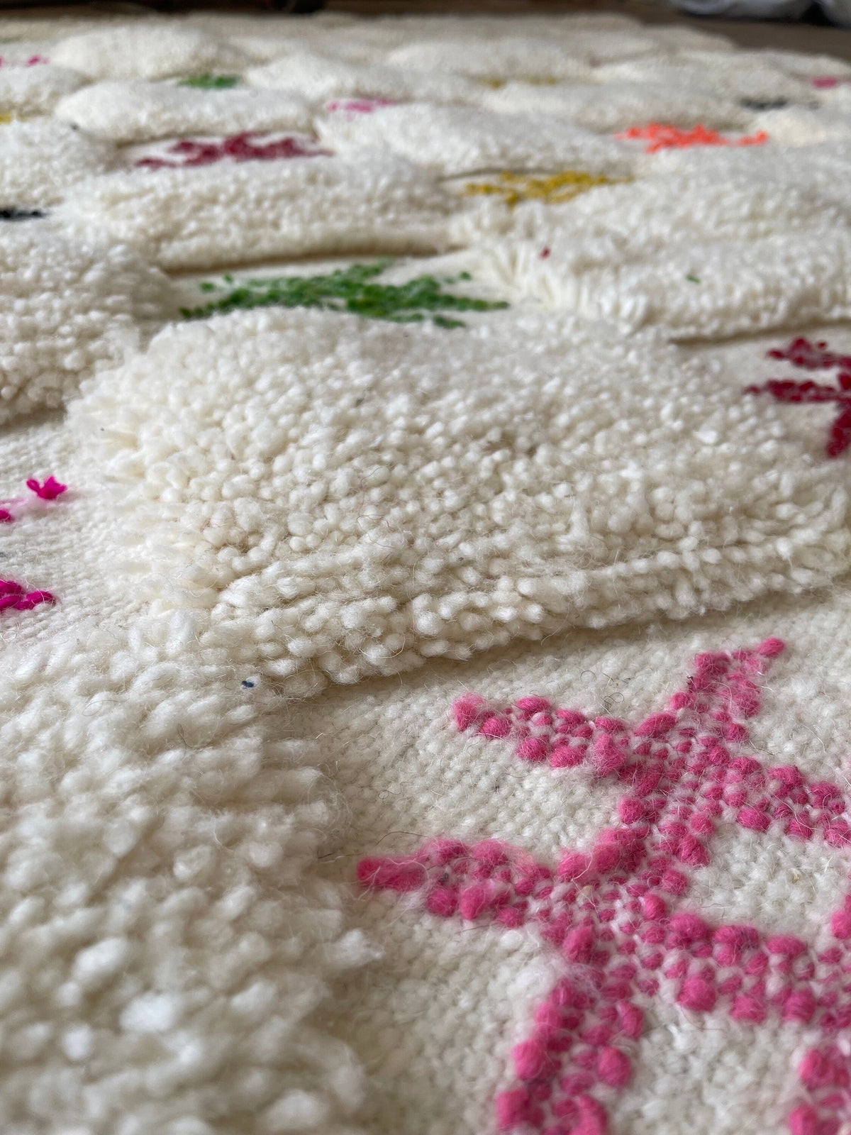 Gros plan sur la laine du tapis berbère Selbira, poil blanc multicolore noué à la main