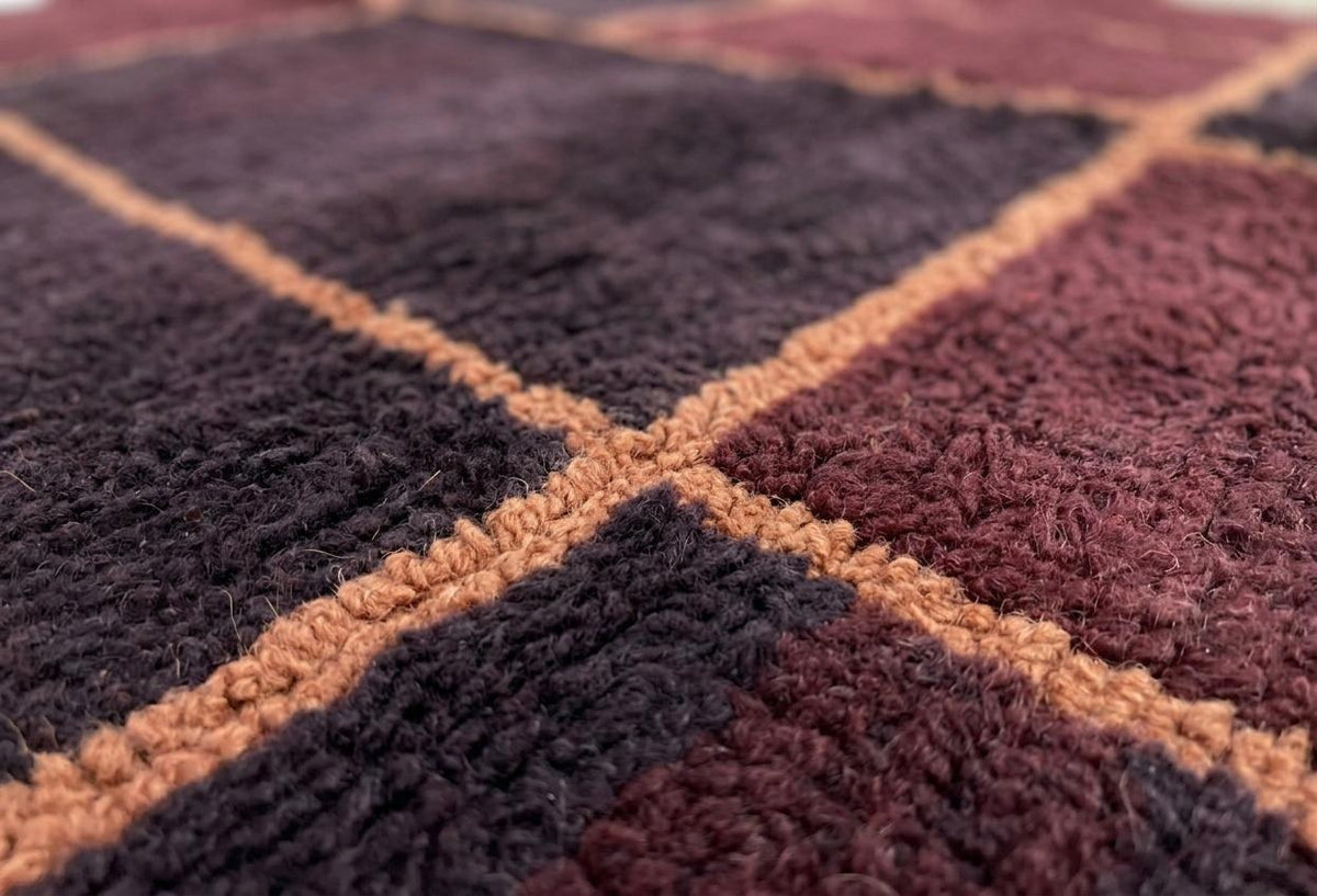 Gros plan sur la laine du tapis berbère Tazgurt, laine de mouton au poil long, bordeaux et prune