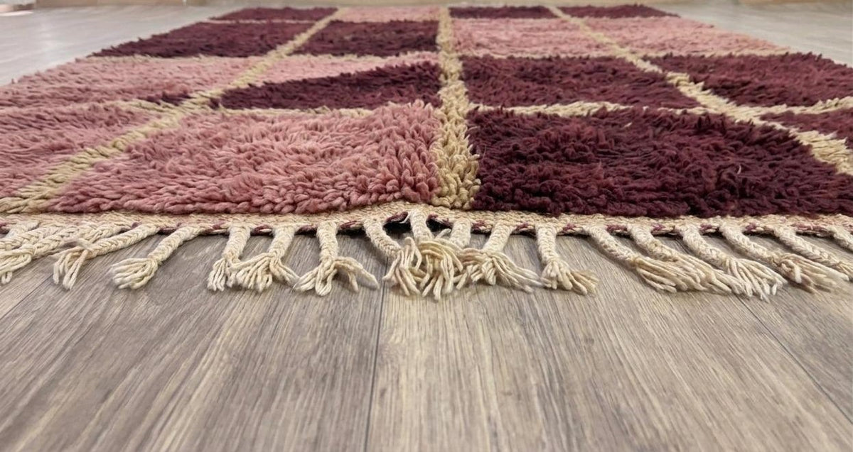 Tapis berbère damier bordeaux et rose Aksel posé au sol vu de côté, noué main au Maroc