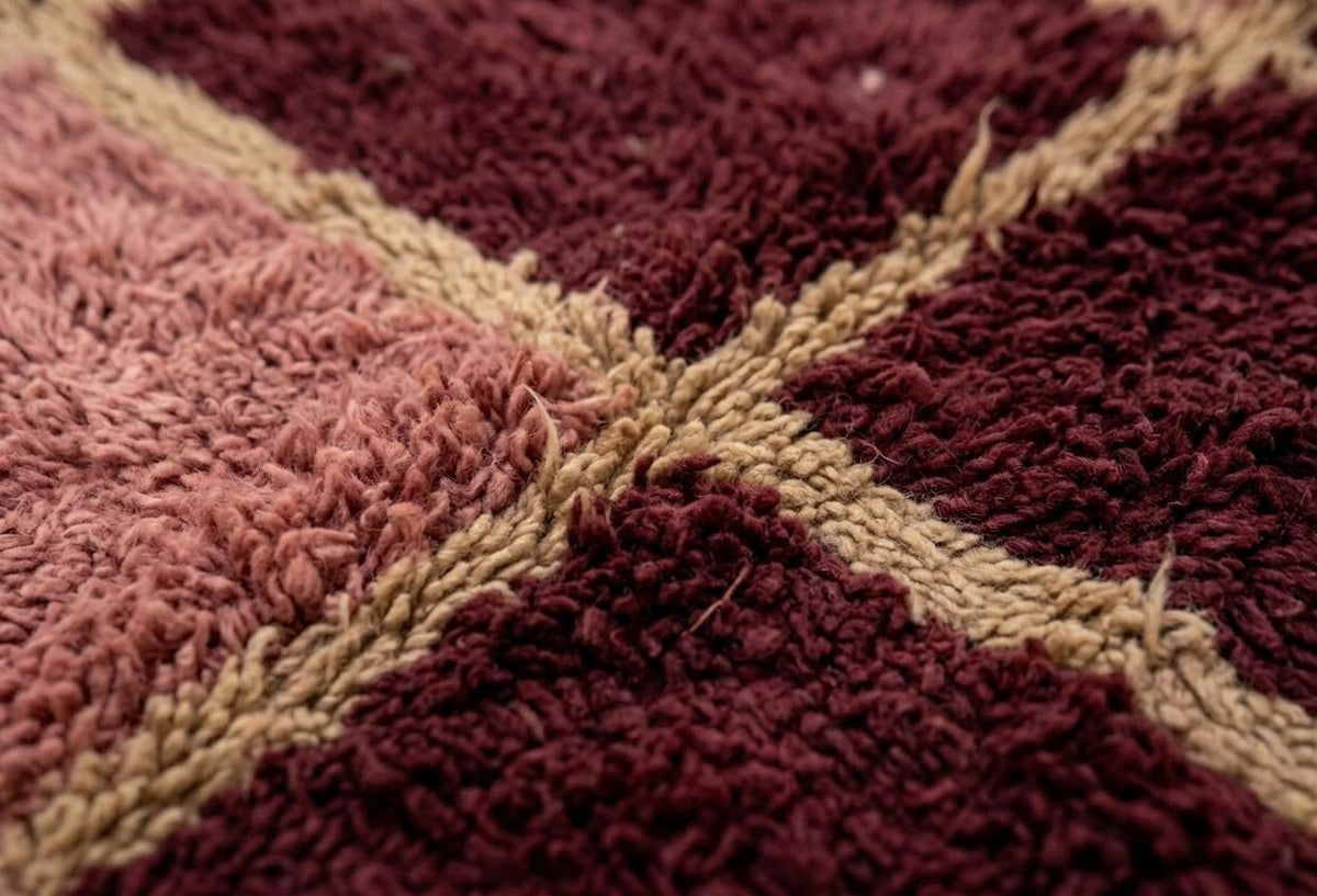 Gros plan sur la laine du tapis berbère Aksel, laine de mouton au poil long, bordeaux et rose