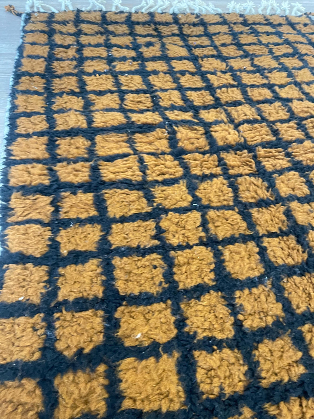 Gros plan sur les franges du tapis berbère Tirgamt, écrues, nouées à la main