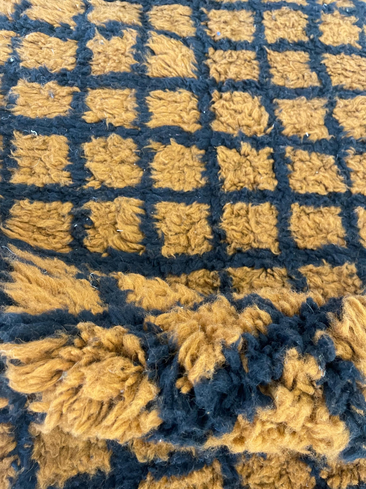 Gros plan sur la laine du tapis berbère Tirgamt, texture de la laine naturelle et nuances du poil