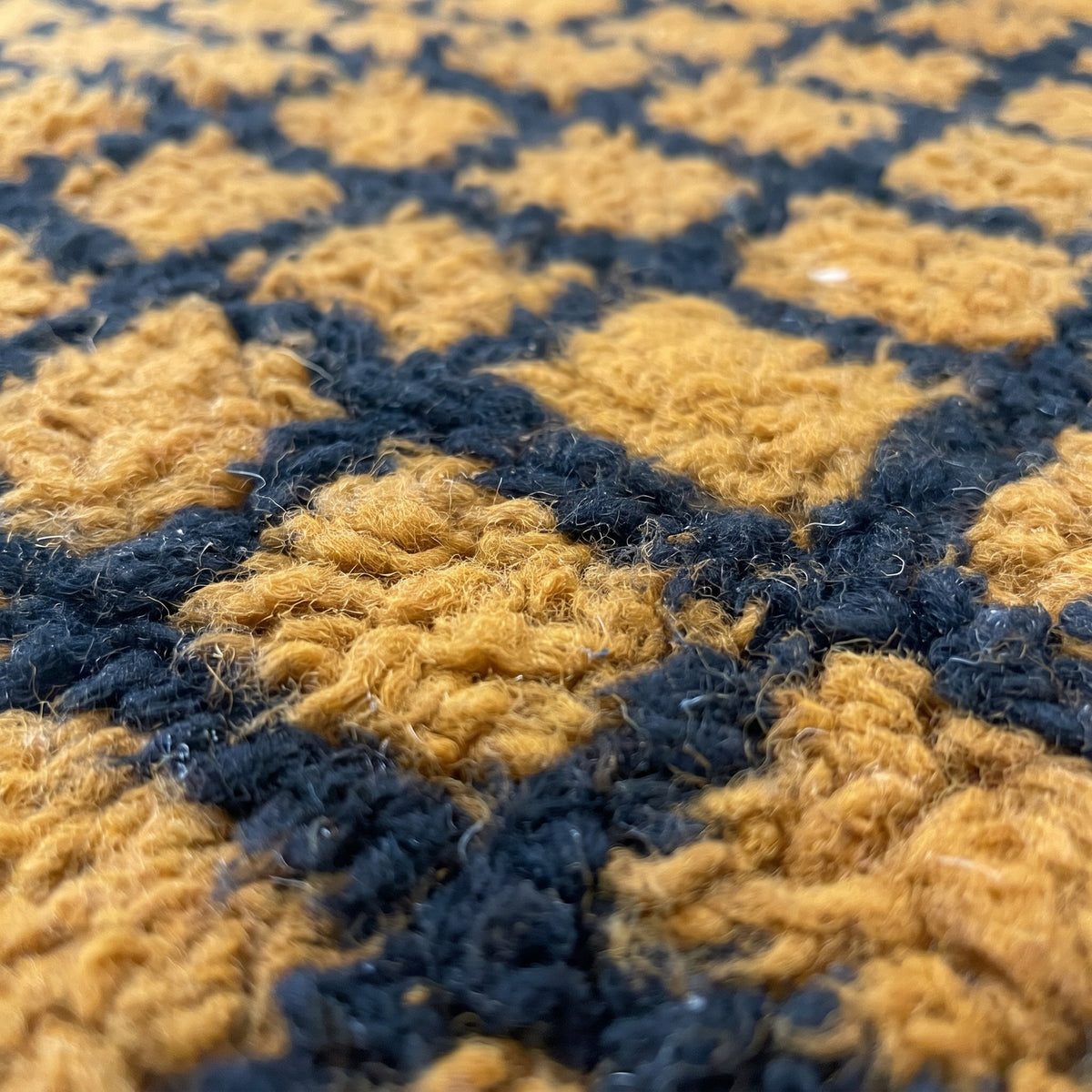 Gros plan sur un motif du tapis berbère Tirgamt, quadrillage noir serré sur toute la surface