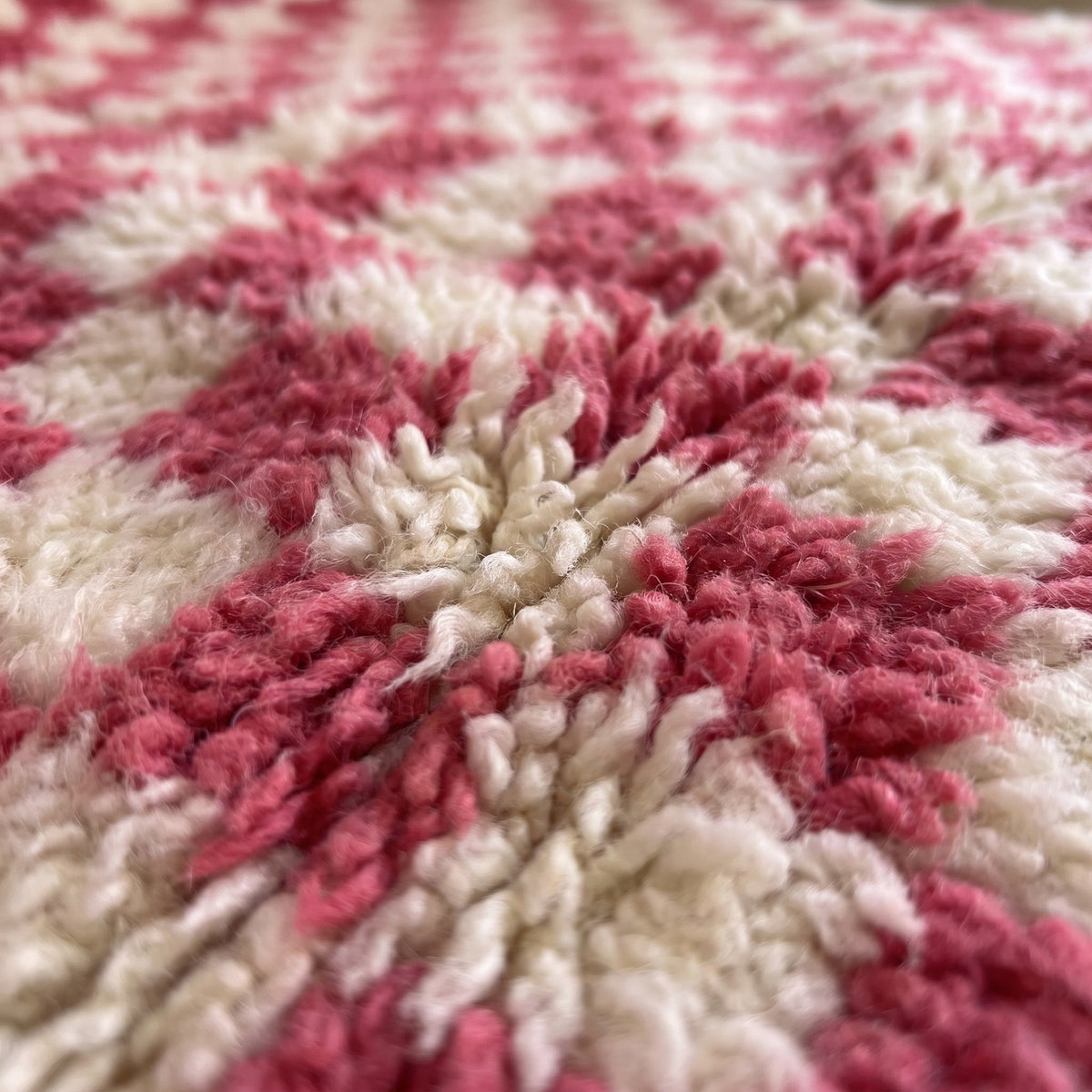 Gros plan sur un motif du tapis berbère Bazlira, damier serré rose framboise et écru