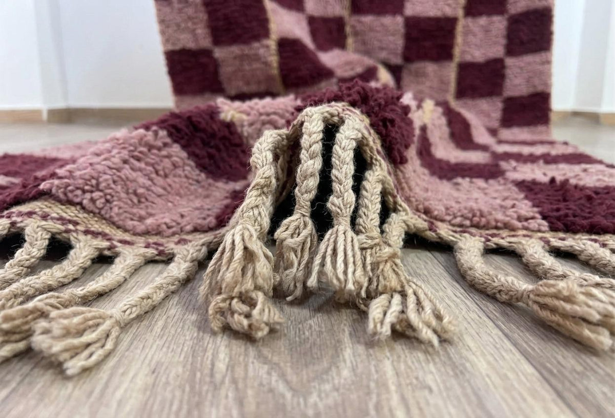 Gros plan sur les franges du tapis berbère Timerza, sable tressées en bas seulement, nouées à la main
