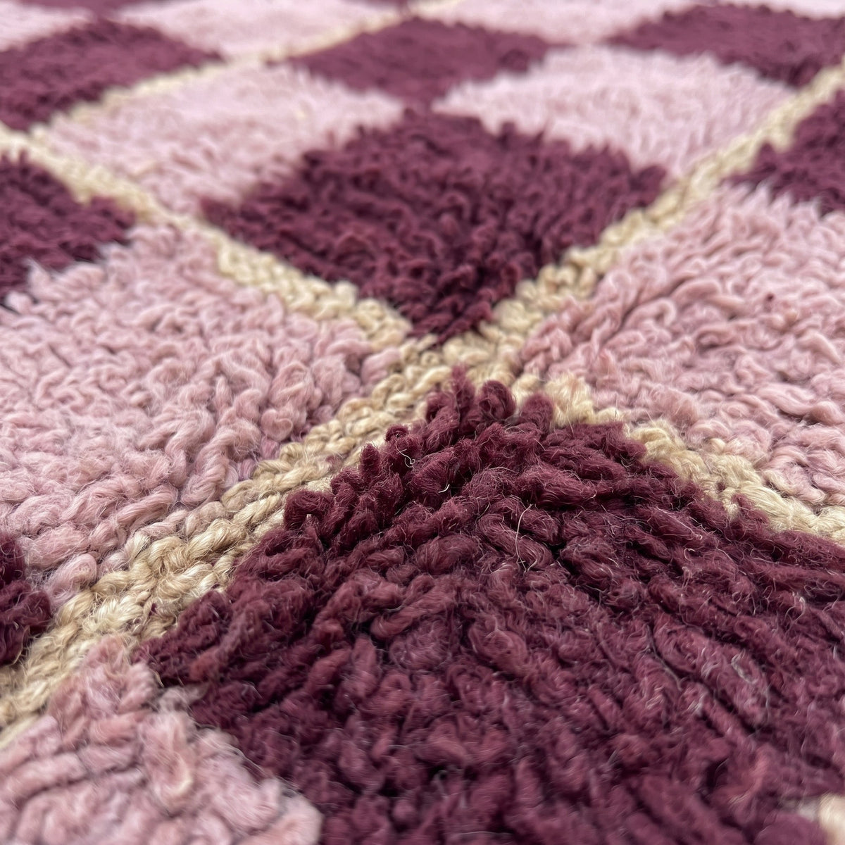 Gros plan sur un motif du tapis berbère Timerza, damier de huit carrés sur dix alternant rose