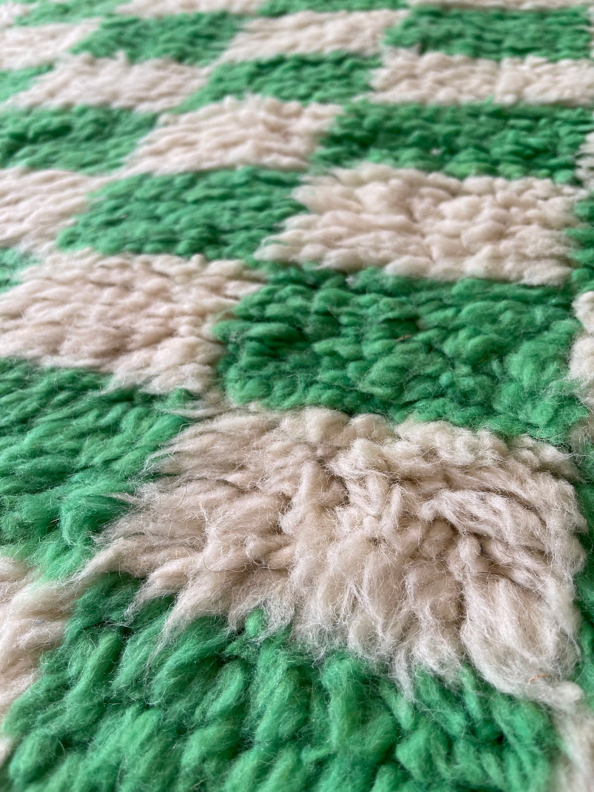 Gros plan sur la laine du tapis berbère Nerloun, poil vert et blanc noué à la main
