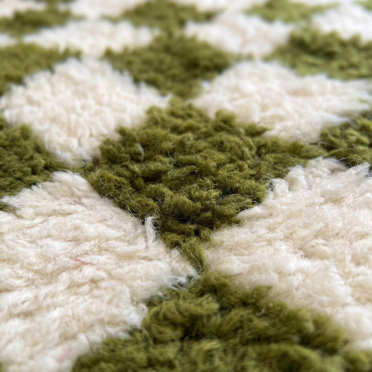 Gros plan sur un motif du tapis berbère Bouskoura, damier régulier vert olive et écru