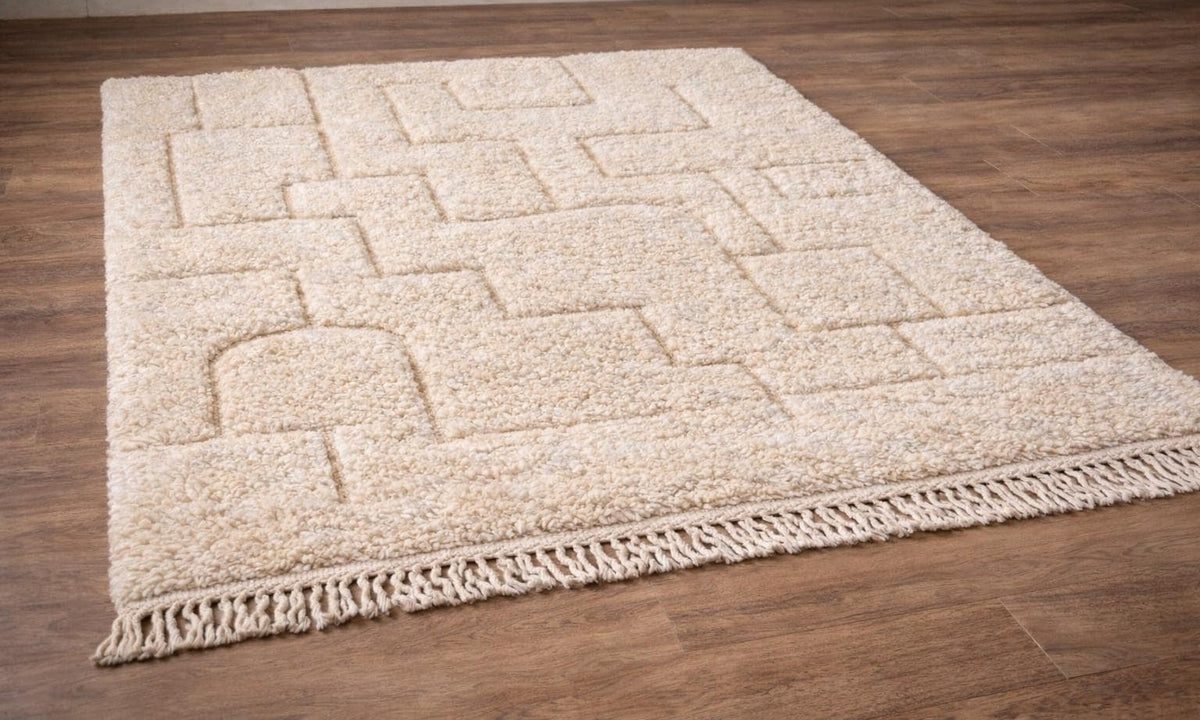 Tapis berbère en relief ivoire Lixus posé au sol vu de côté, noué main au Maroc