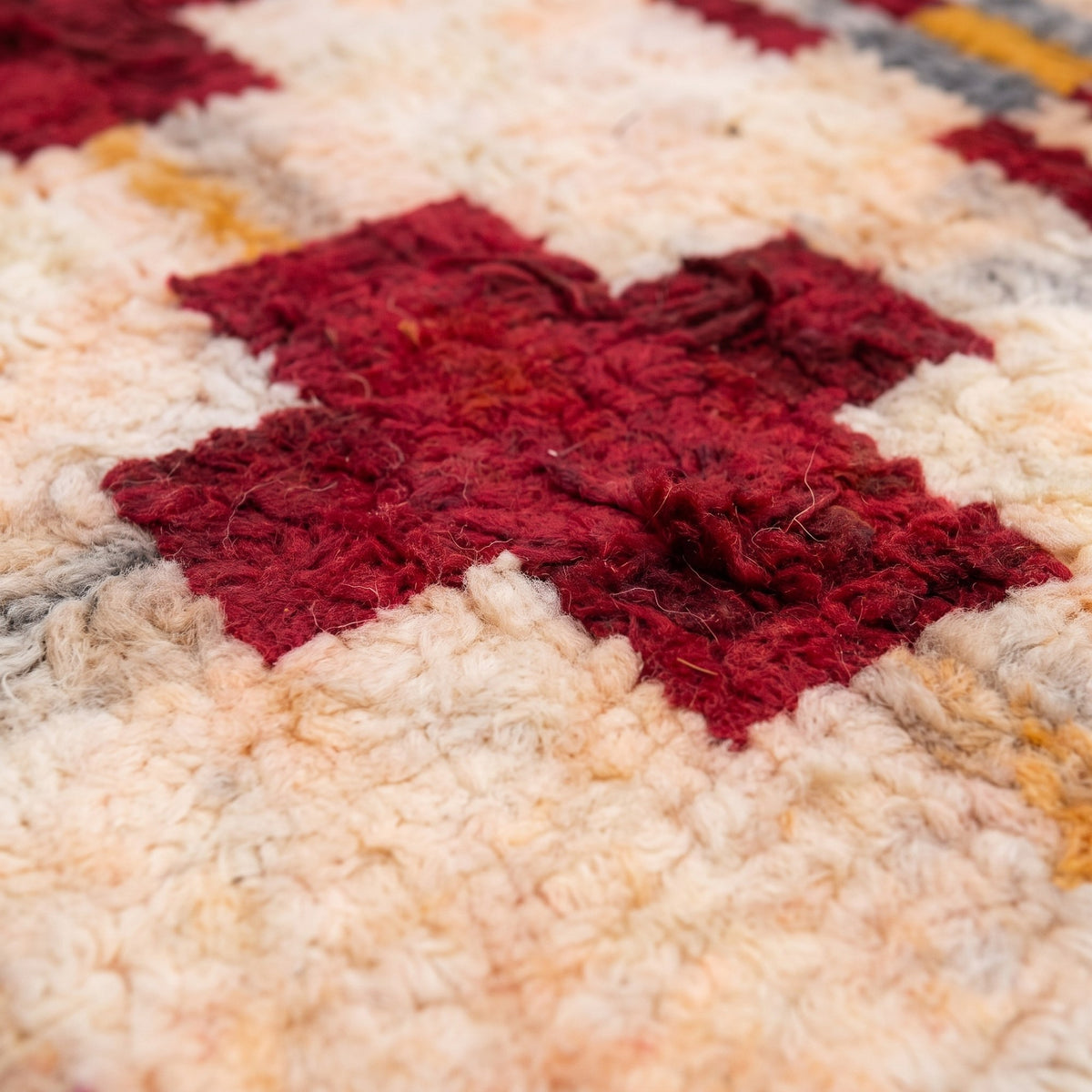 Gros plan sur un motif du tapis berbère Zerekten, fond écru rosé, grille de croix bordeaux