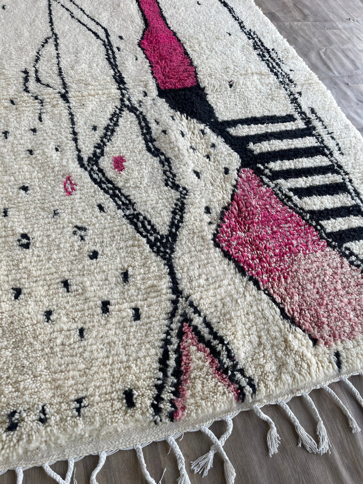 Gros plan sur les franges du tapis berbère Timit, blanches en bas seulement, nouées à la main