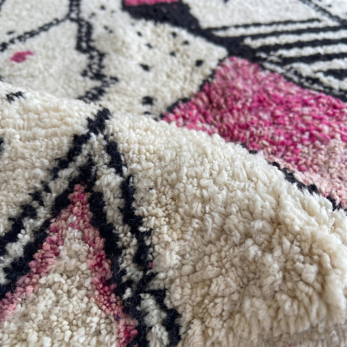 Gros plan sur un motif du tapis berbère Timit, fines lignes noires, bouteille en double trait