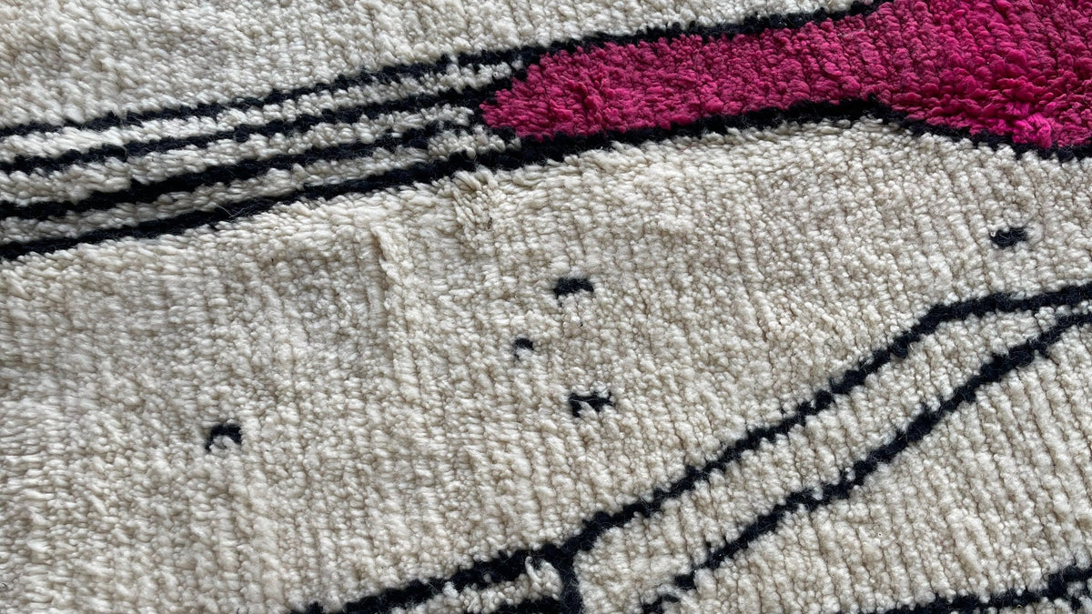 Gros plan sur la laine du tapis berbère Timit, poil blanc et fuchsia noué à la main