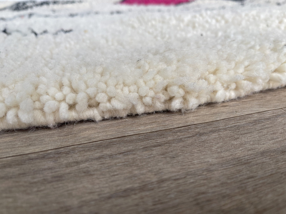 Gros plan sur la laine du tapis berbère Tira, laine de mouton au poil long, blanche et fuchsia
