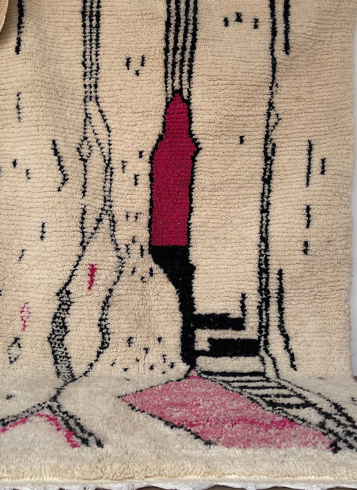 Gros plan sur un détail du tapis berbère Tira, poil long et motif blanc et fuchsia vus de près