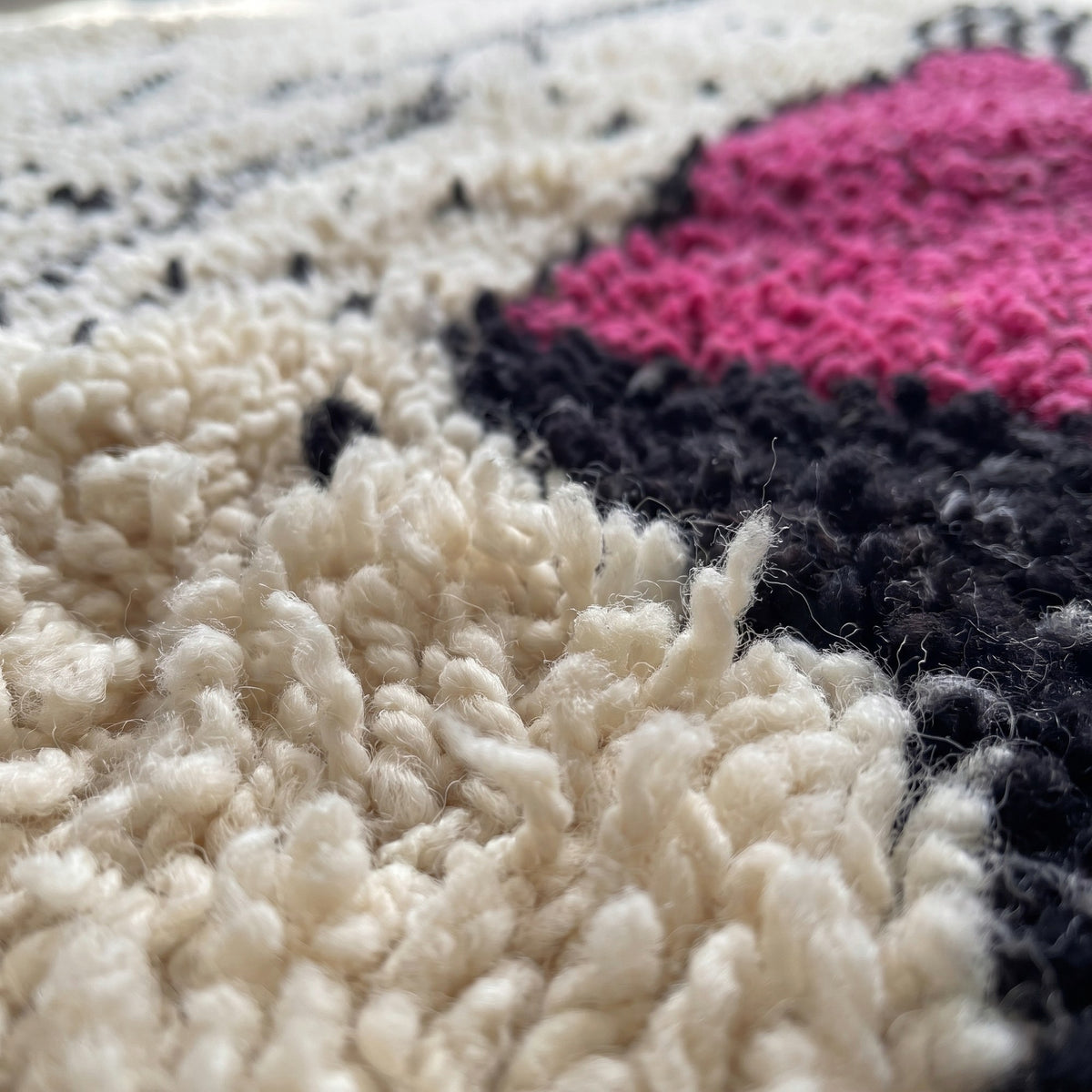 Gros plan sur un motif du tapis berbère Tira, fond ivoire, au centre colonne fuchsia