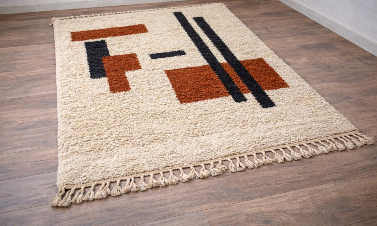 Meskala graphic Berber rug in white and terracotta, on the floor, seen from the side at an angle, hand-knotted in Morocco