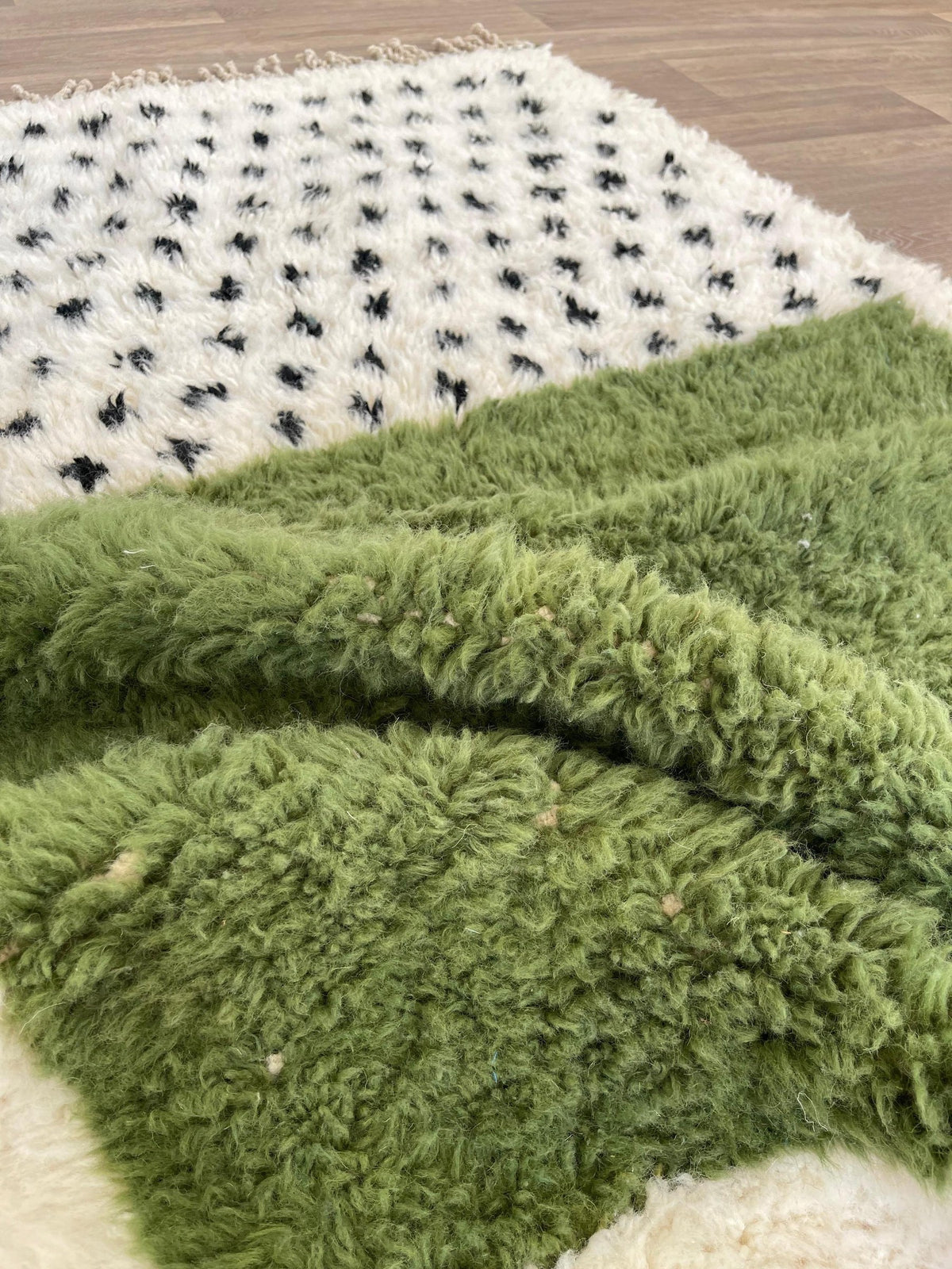 Gros plan sur la laine du tapis berbère Tafniwa, laine de mouton au poil long, blanche et verte