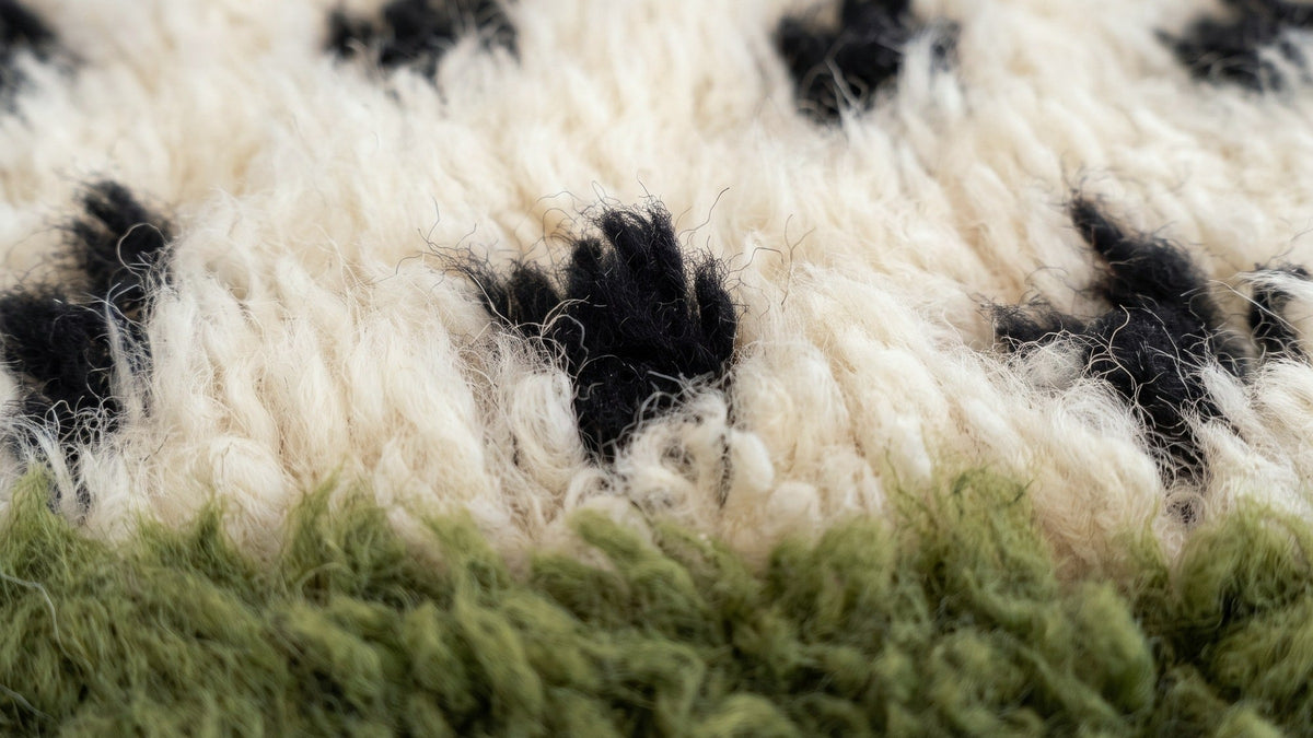 Gros plan sur la laine du tapis berbère Tafniwa, poil blanc et vert noué à la main