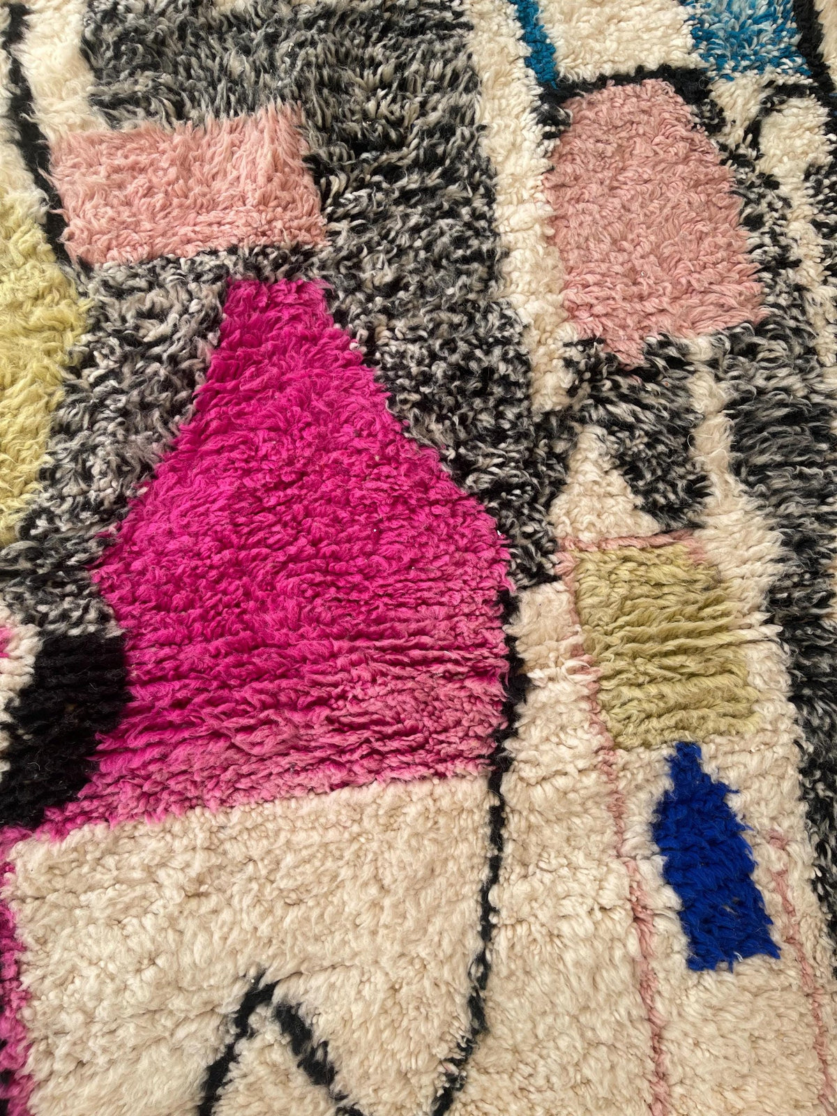 Gros plan sur la laine du tapis berbère Lozmira, relief de la laine et du motif à la lumière