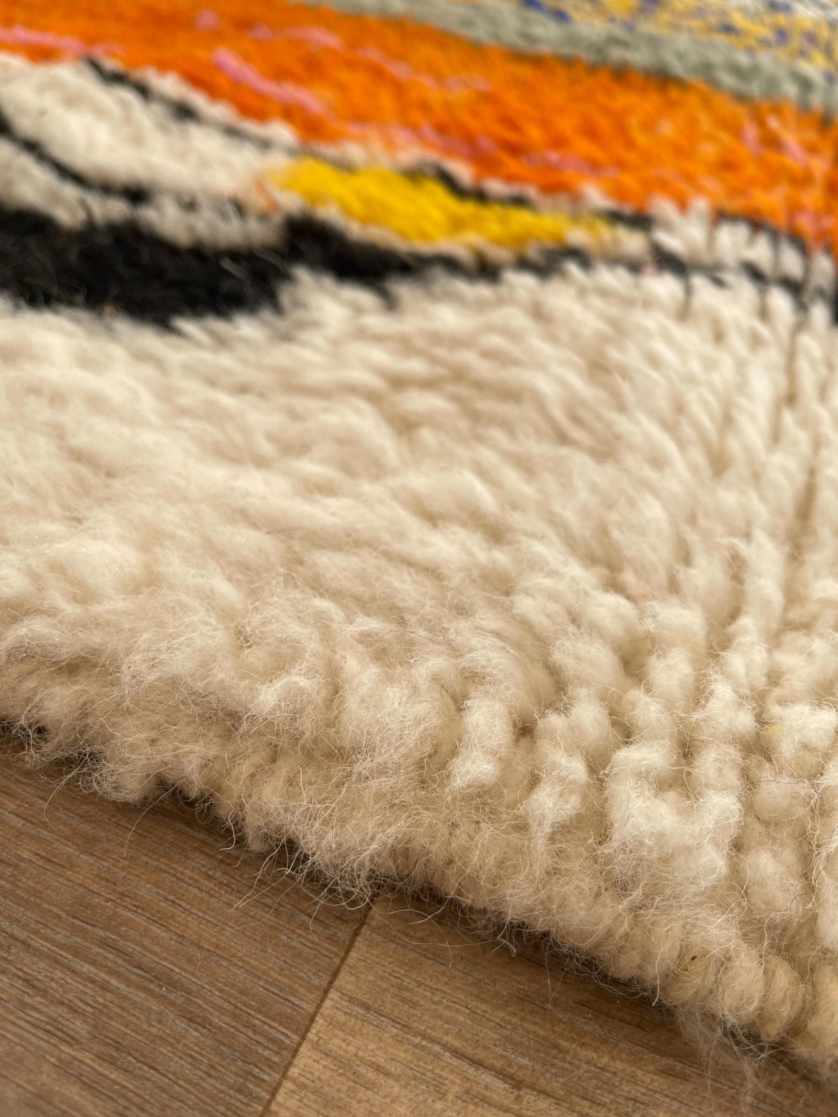 Gros plan sur la laine du tapis berbère Tamgrout, poil blanc multicolore noué à la main