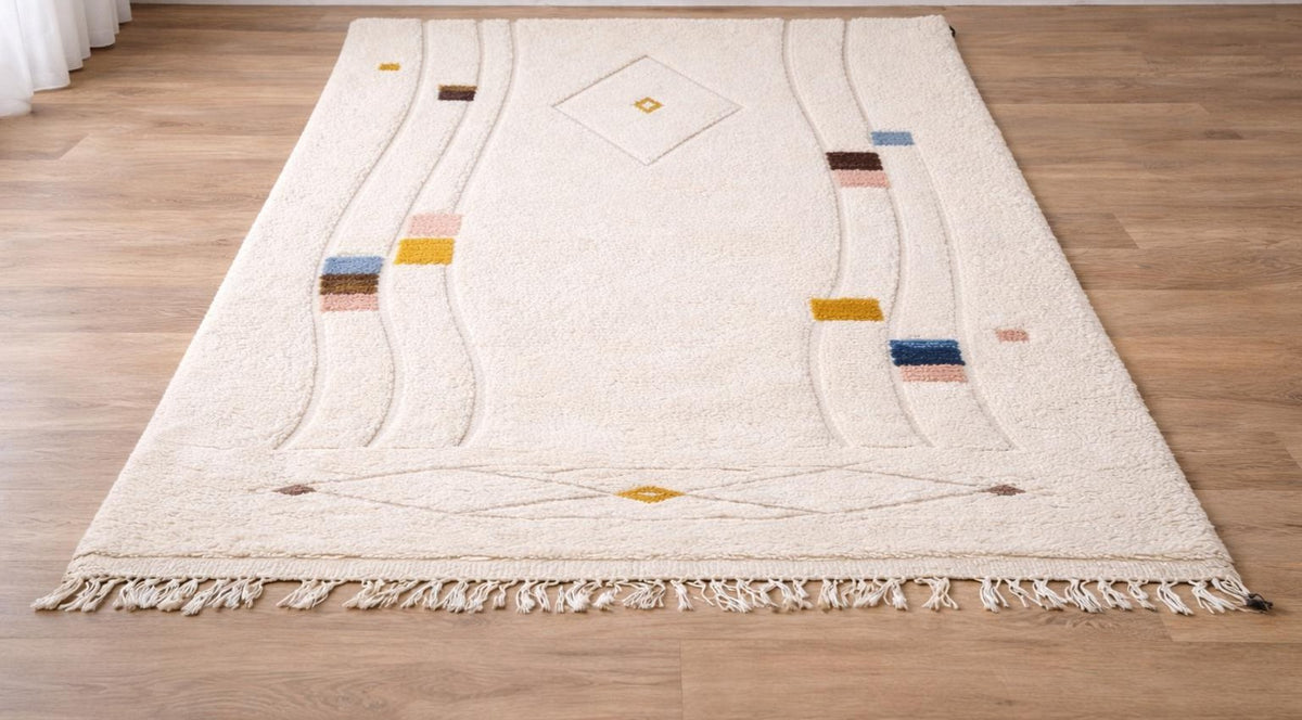 Tapis berbère graphique blanc Tawenza posé au sol vu de côté, noué main au Maroc
