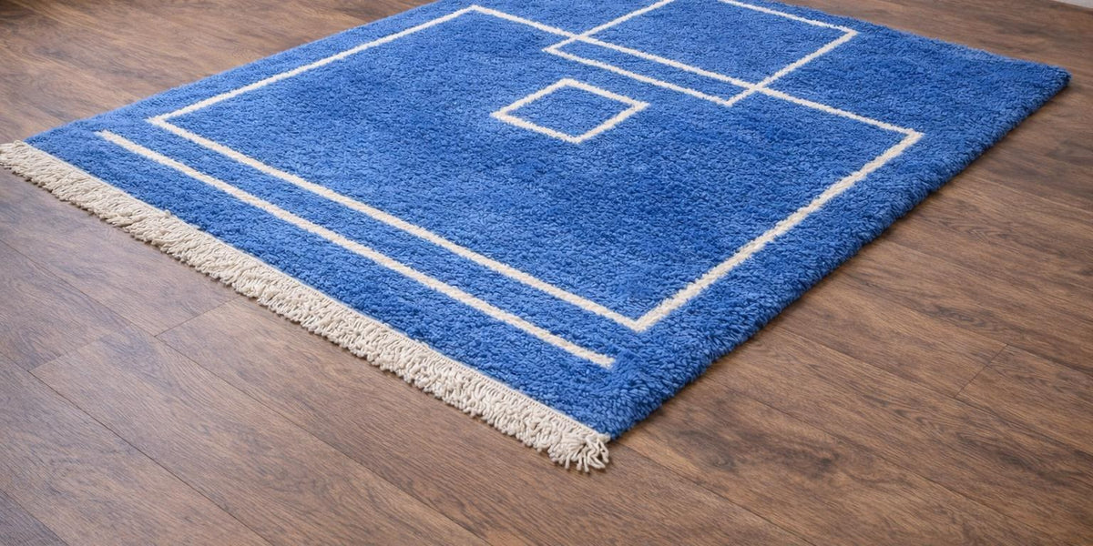 Tapis berbère graphique bleu Amdun posé au sol vu de côté, noué main au Maroc