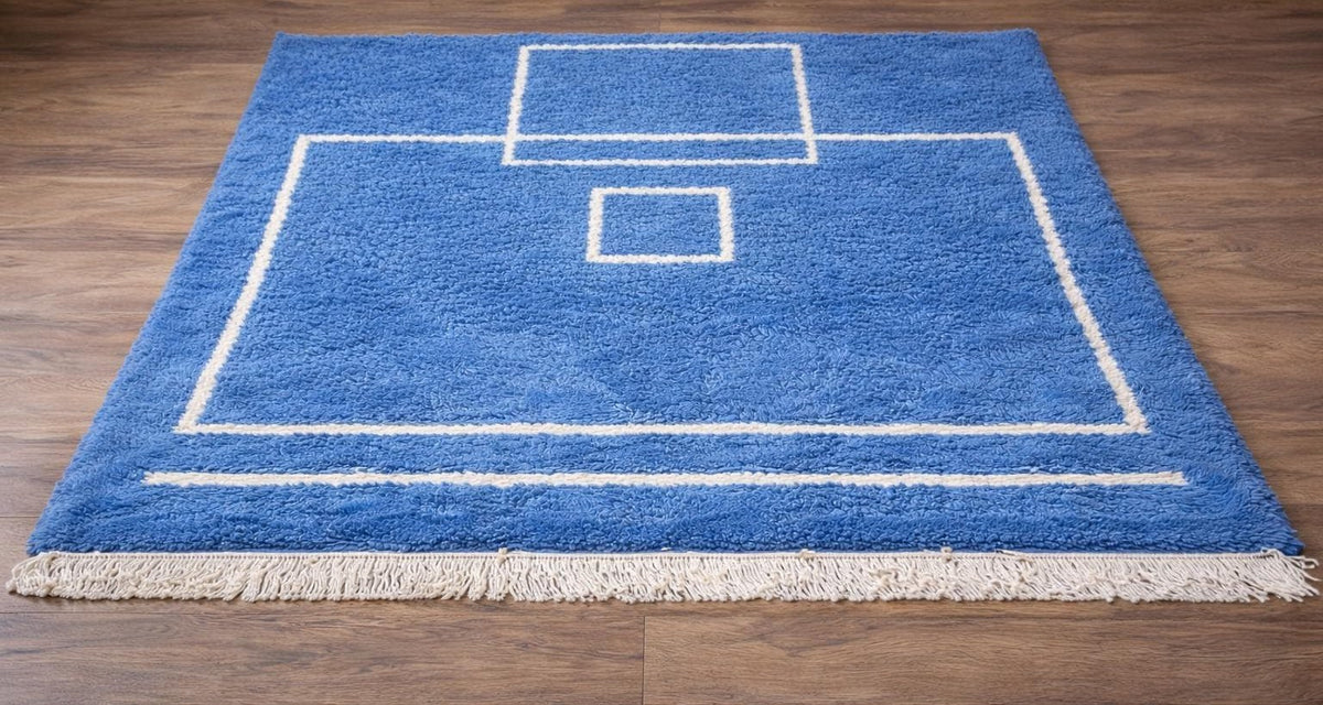 Tapis berbère graphique bleu Amdun posé au sol vu en biais, noué main au Maroc