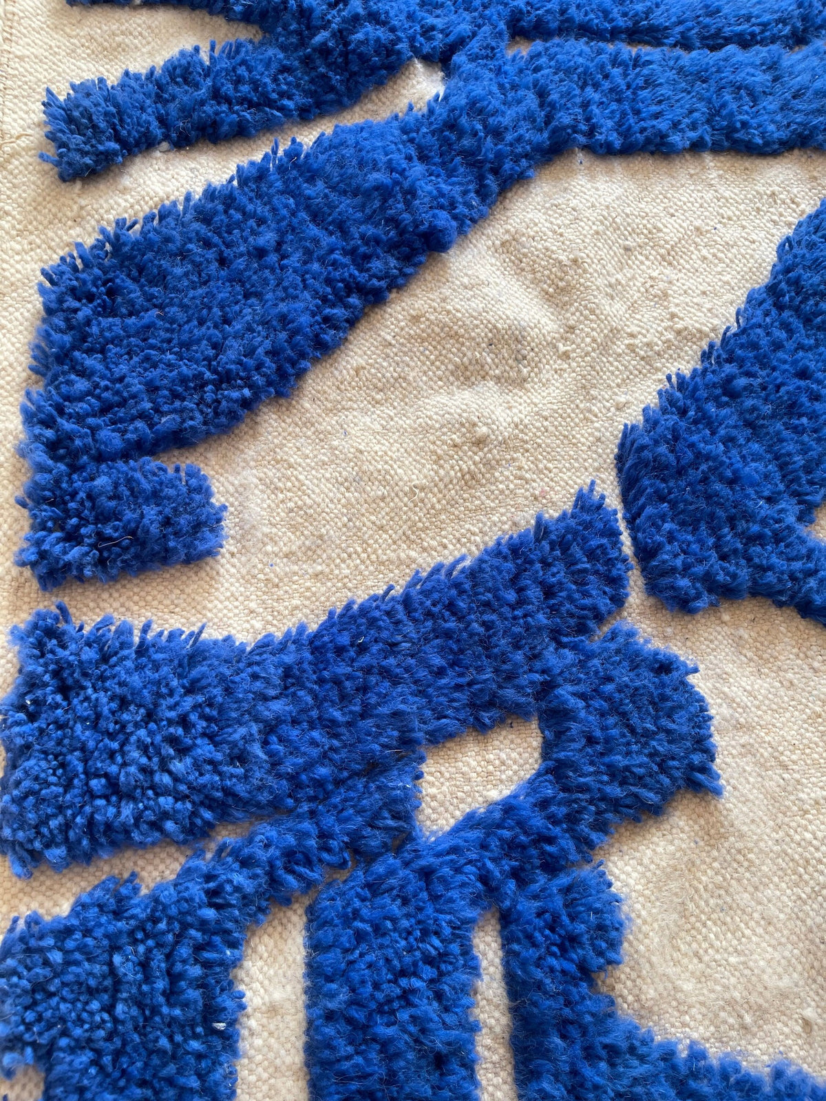 Gros plan sur la laine du tapis berbère Isli, nœuds serrés et tracé du motif de près