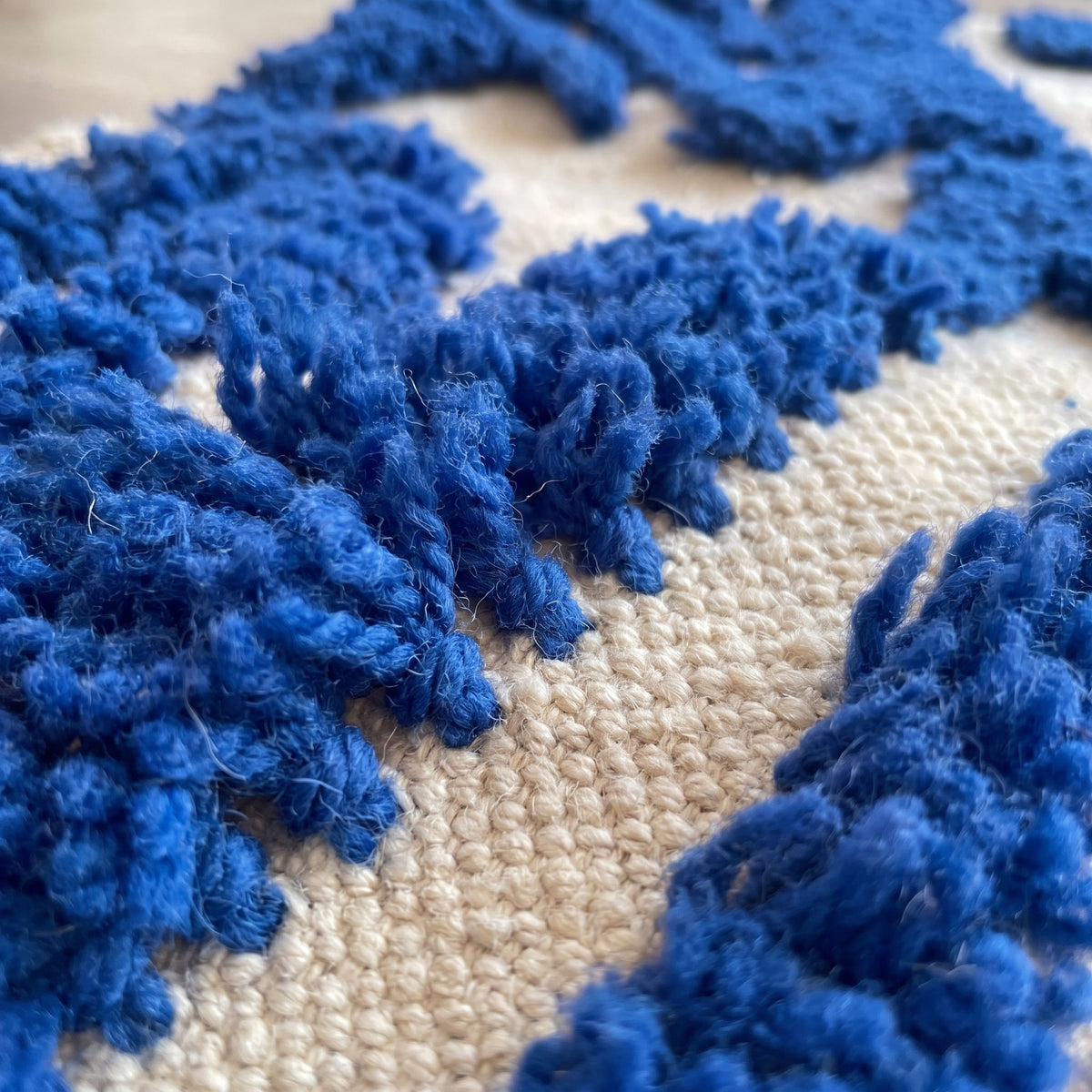 Gros plan sur un motif du tapis berbère Isli, grands traits bleu vif à poil long épais