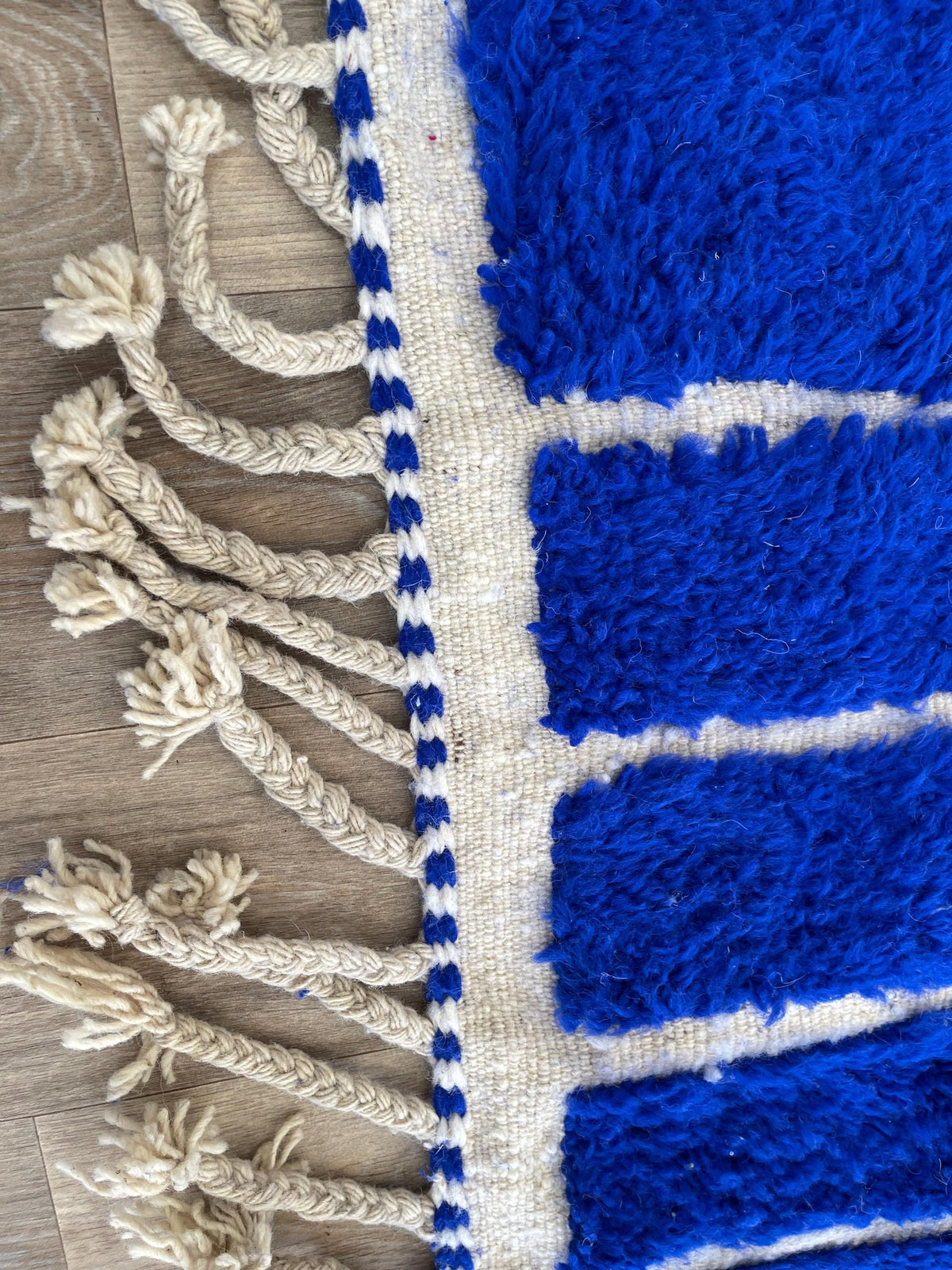 Gros plan sur les franges du tapis berbère Aghmat, écrues, nouées à la main