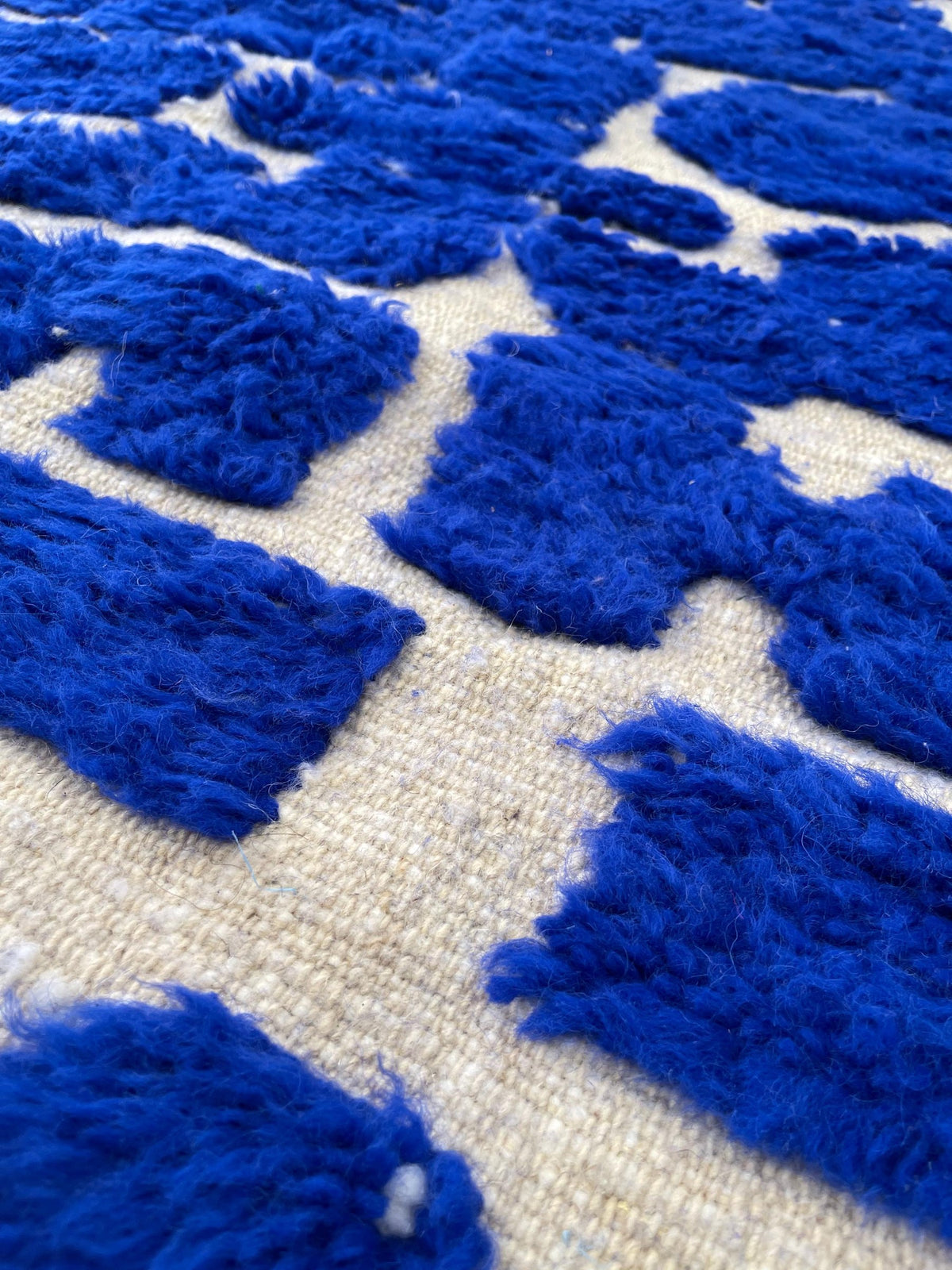 Gros plan sur la laine du tapis berbère Aghmat, poil bleu roi noué à la main