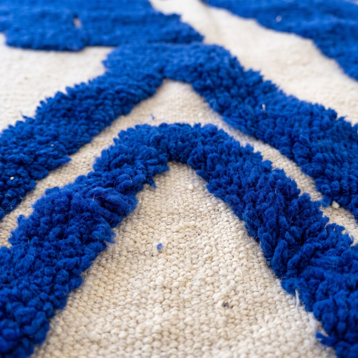 Gros plan sur un motif du tapis berbère Loukkos, fond écru ras, symboles bleu roi en relief