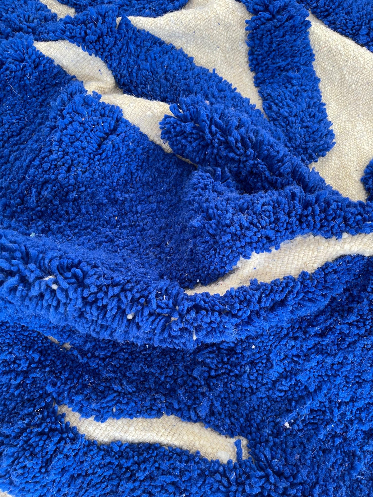 Gros plan sur la laine du tapis berbère Martil, laine de mouton au poil long, bleu roi