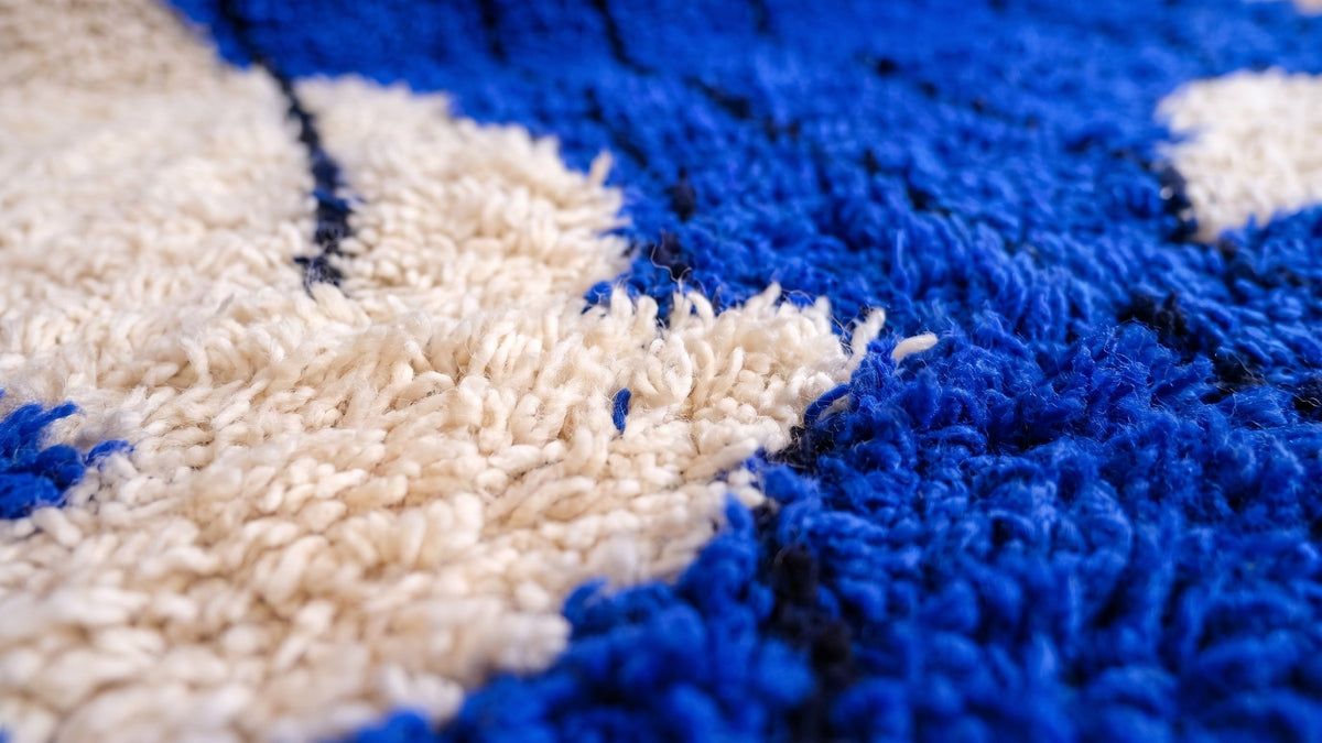 Gros plan sur la laine du tapis berbère Tizgane, poil bleu roi noué à la main