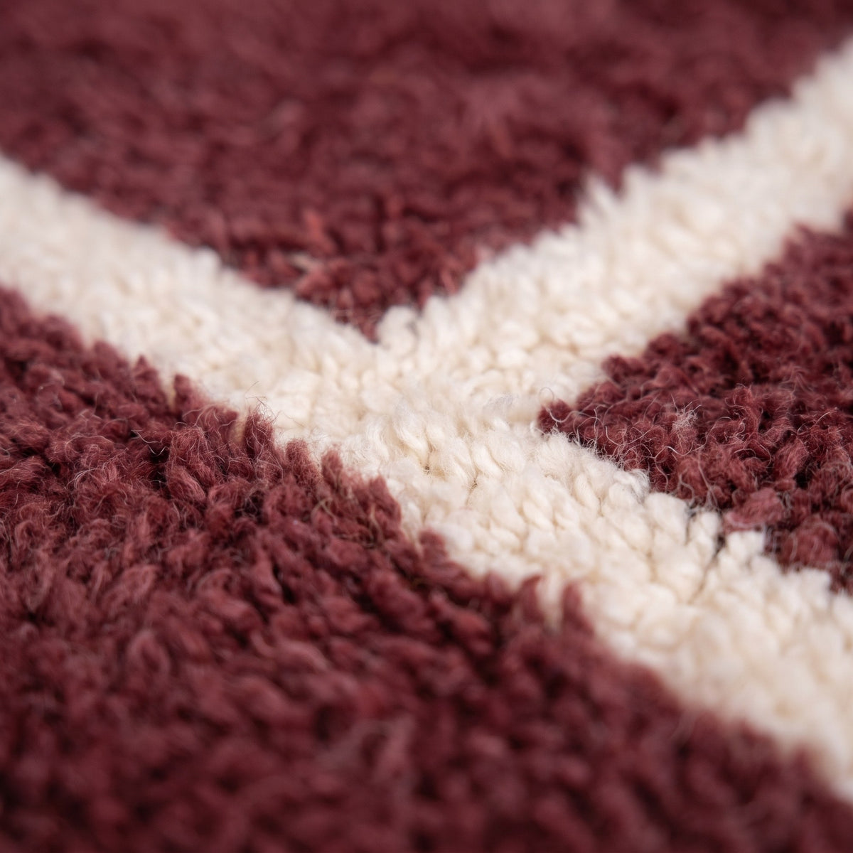 Gros plan sur un motif du tapis berbère Kalah, champ bordeaux à poil moyen dense