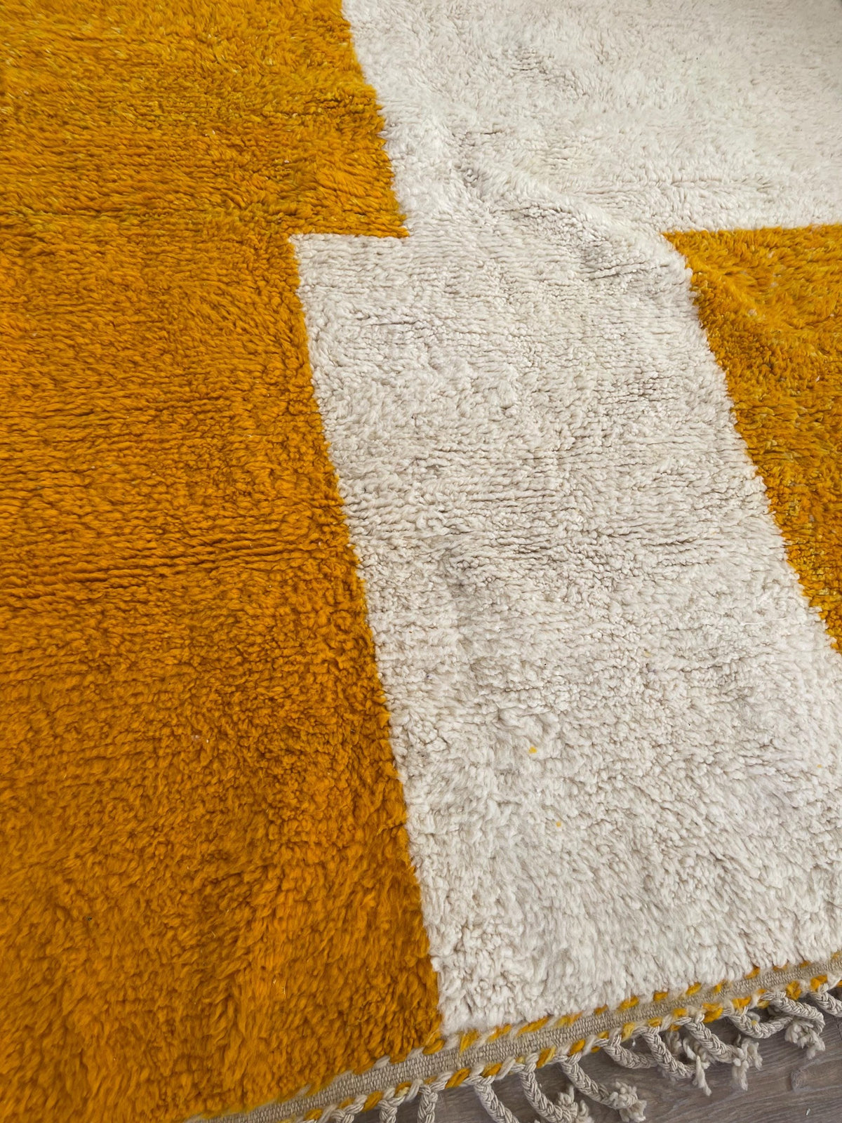 Gros plan sur un détail du tapis berbère Midelt, poil moyen et motif moutarde et blanc vus de près