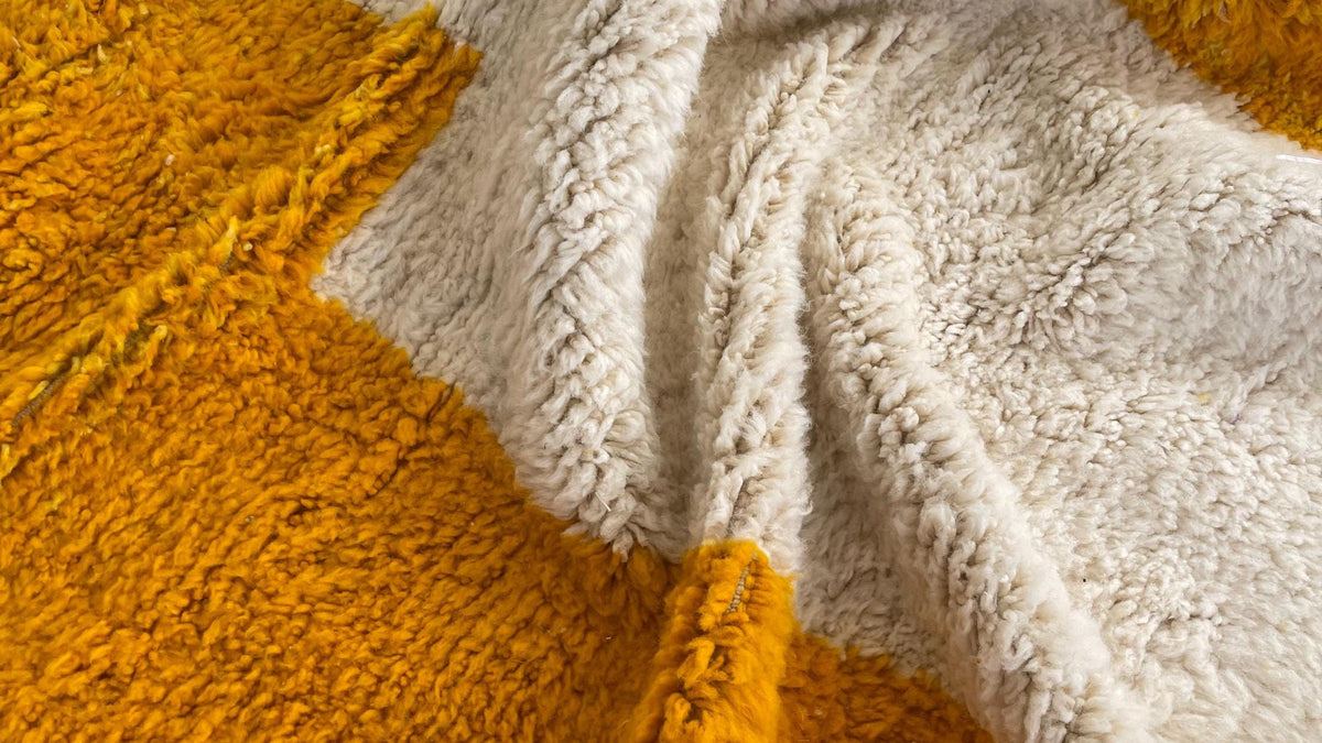 Gros plan sur la laine du tapis berbère Midelt, poil moutarde et blanc noué à la main