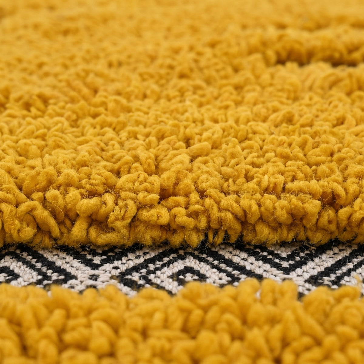 Gros plan sur un motif du tapis berbère Ilzan, base tissée plate à petits losanges noir