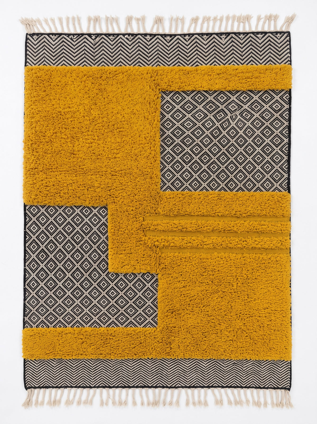 Tapis berbère graphique moutarde Ilzan vu à plat, base tissée plate à petits losanges noir et écru, franges écrues