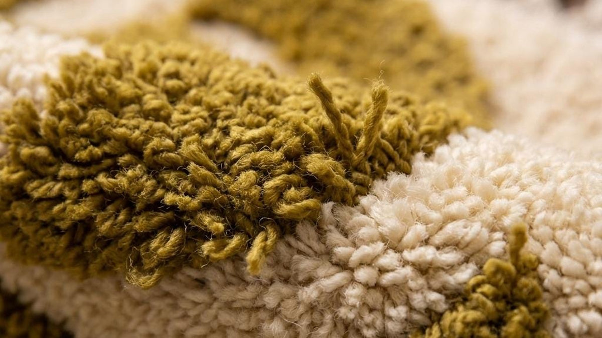 Gros plan sur la laine du tapis berbère Tagdilt, poil moutarde noué à la main