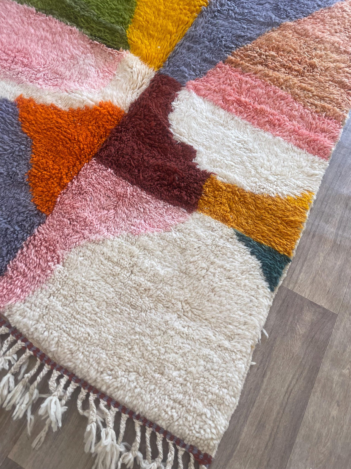 Gros plan sur le coin relevé du tapis berbère Aseggas, épaisseur du poil long et dos tissé à la main