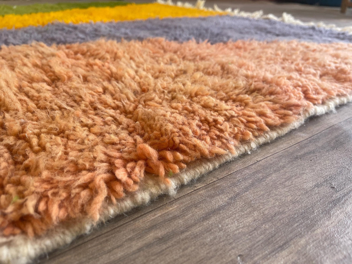 Gros plan sur la laine du tapis berbère Aseggas, nœuds serrés et tracé du motif de près