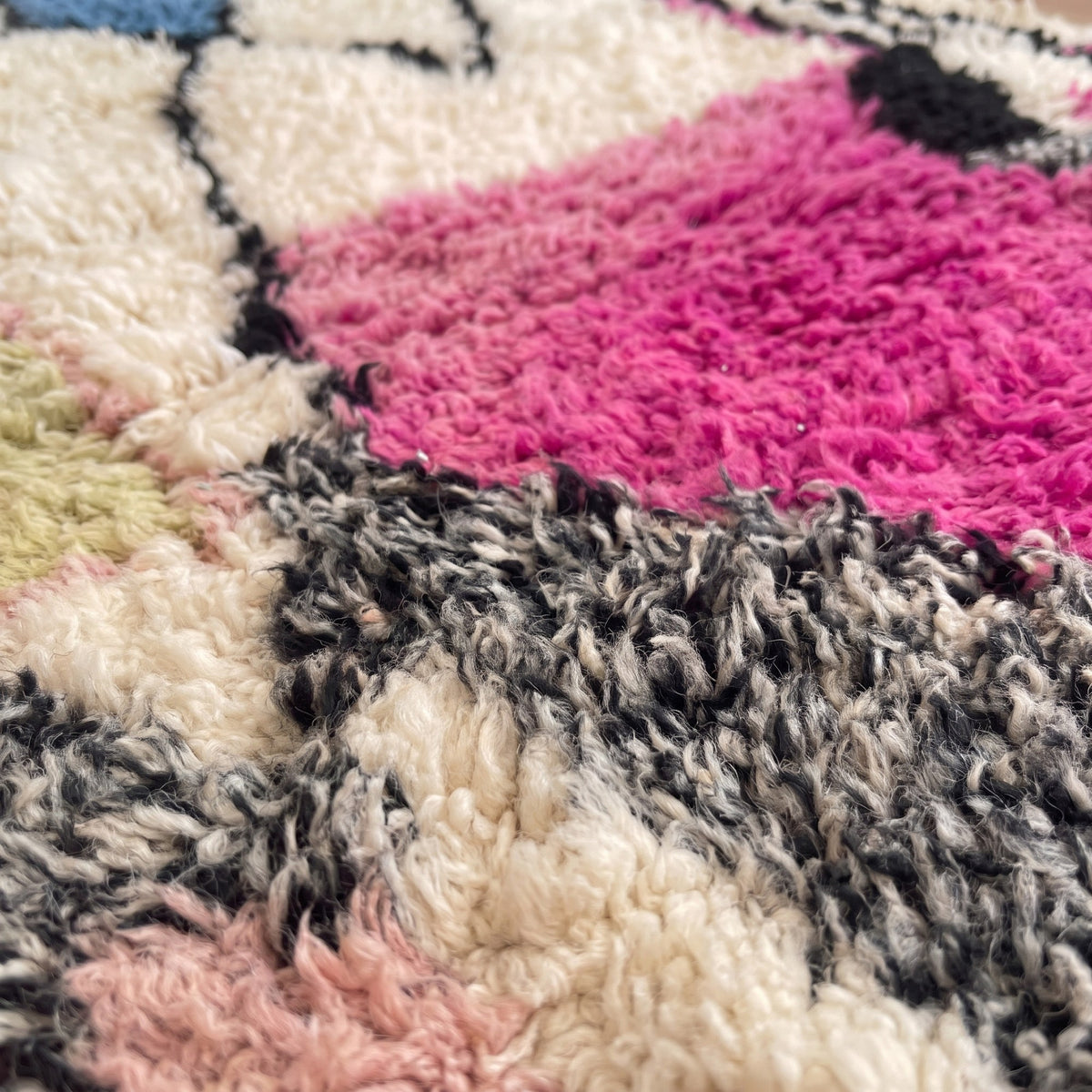 Gros plan sur un motif du tapis berbère Ijoukak, fond écru et gris chiné cerné de noir