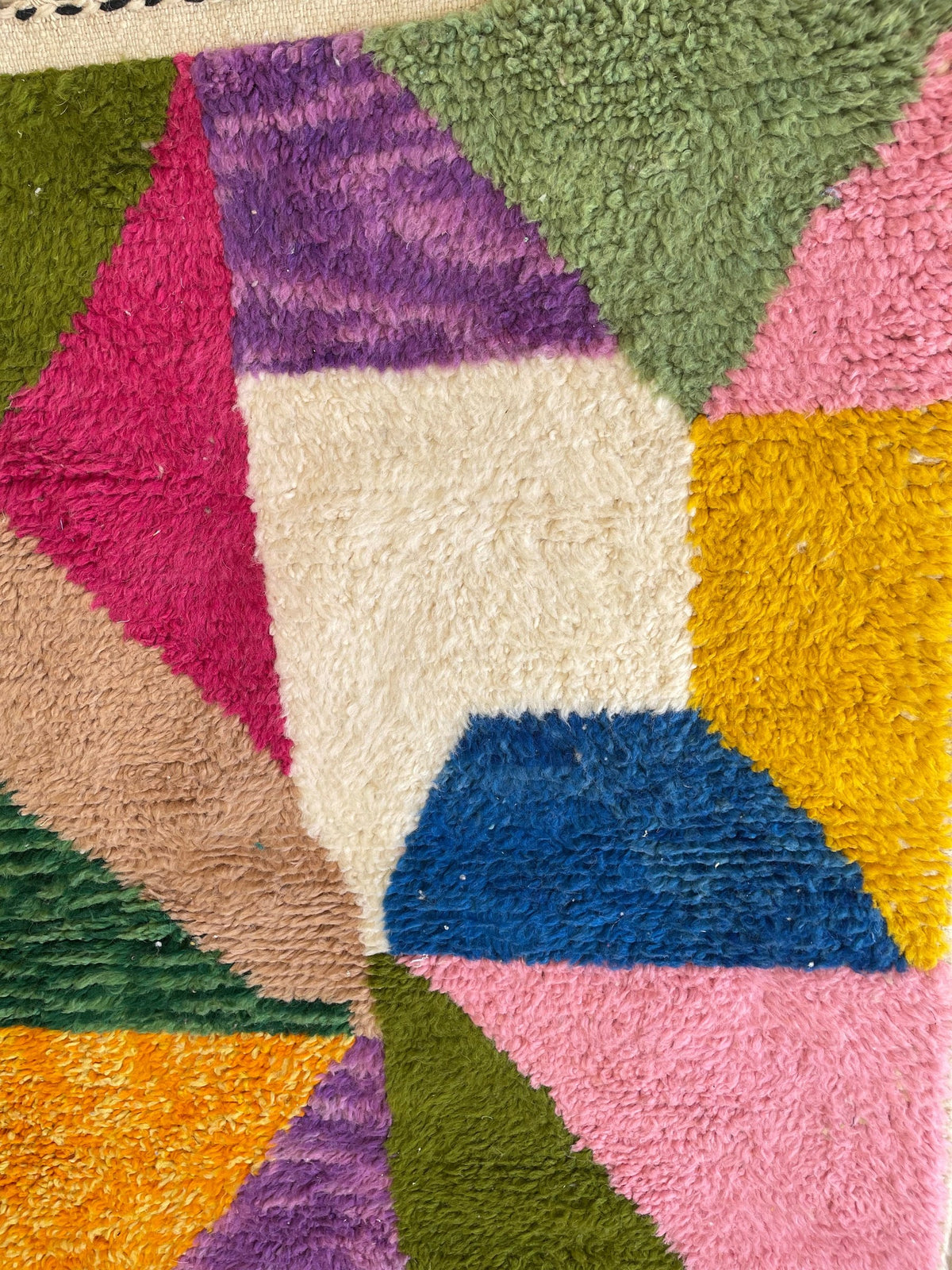 Gros plan sur un détail du tapis berbère Mezrouan, poil long et motif multicolore vus de près