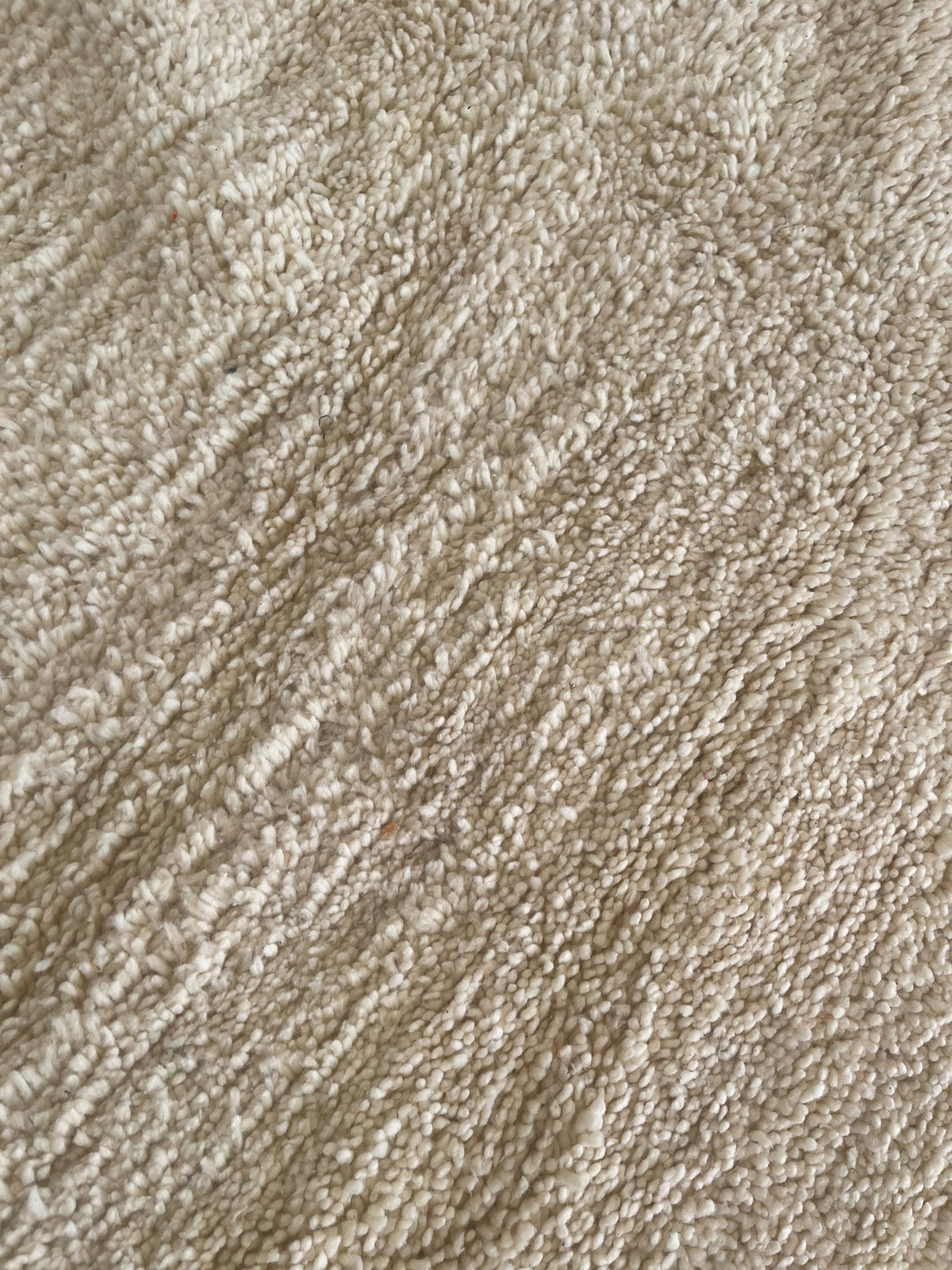 Gros plan sur la laine du tapis berbère Nassour, laine de mouton au poil long, multicolore